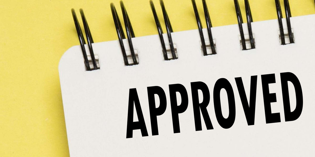 Approved stamp on a spiral notepad with a yellow background, symbolizing confirmation, authorization, and business approval.