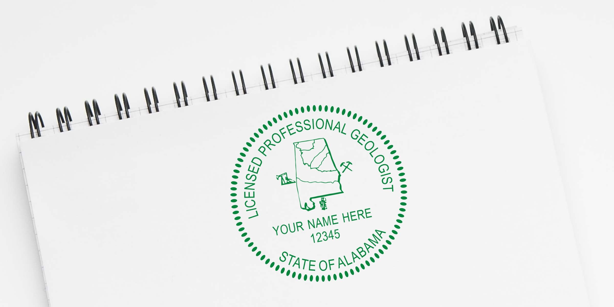Alabama Geologist Seal with licensed geologist stamp, state map, and mining tools on white spiral notebook, symbolizing geological certification in Alabama.