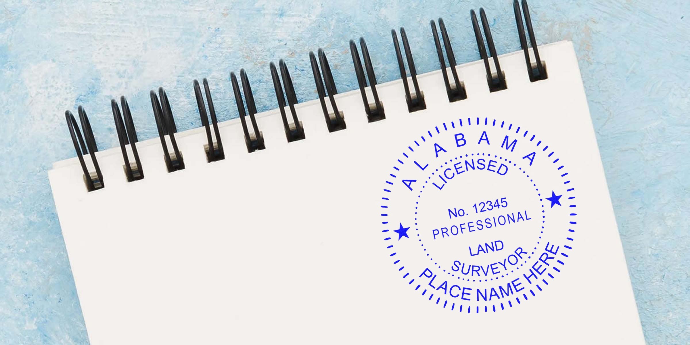AL PLS embossing seal of licensed Alabama professional land surveyor stamped on white spiral notebook, embossing seal edges visible.