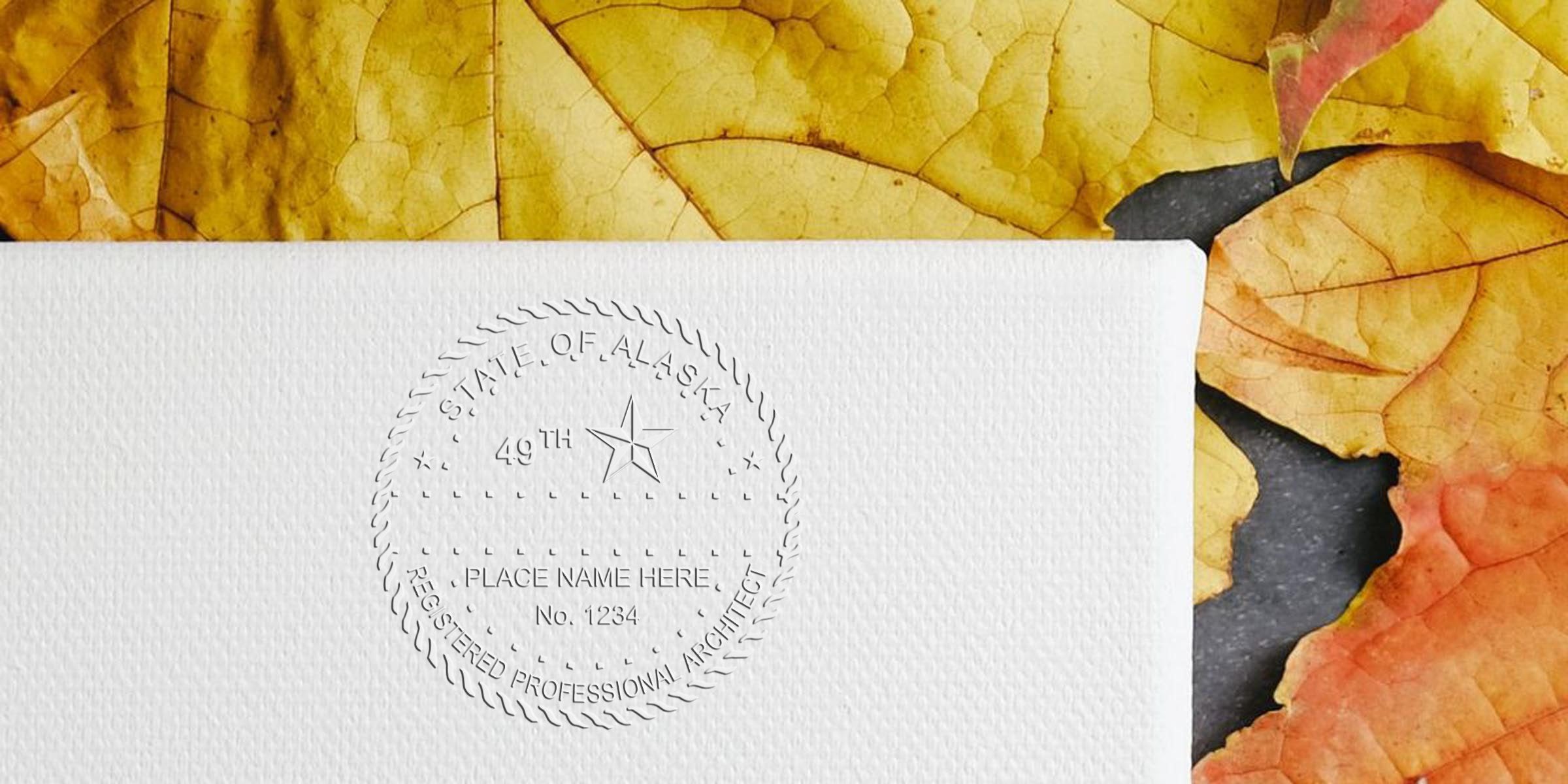 Embossed Alaska architect seal on white paper with autumn leaves, highlighting Alaska architect stamp cost and pricing.