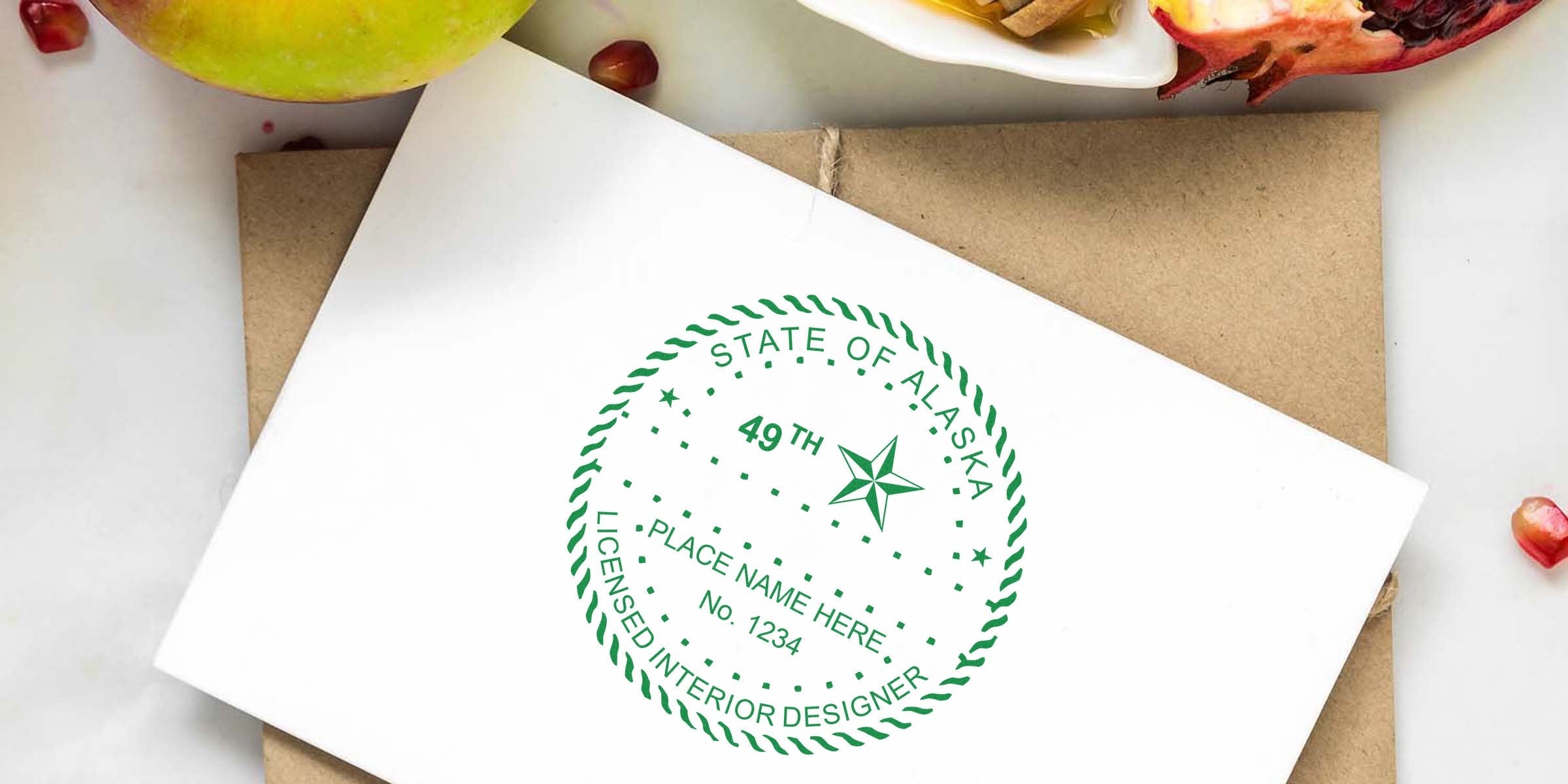 State of Alaska Interior Designer Stamp on white envelope with green apple and pomegranate seeds, highlighting Alaska's creative tools.