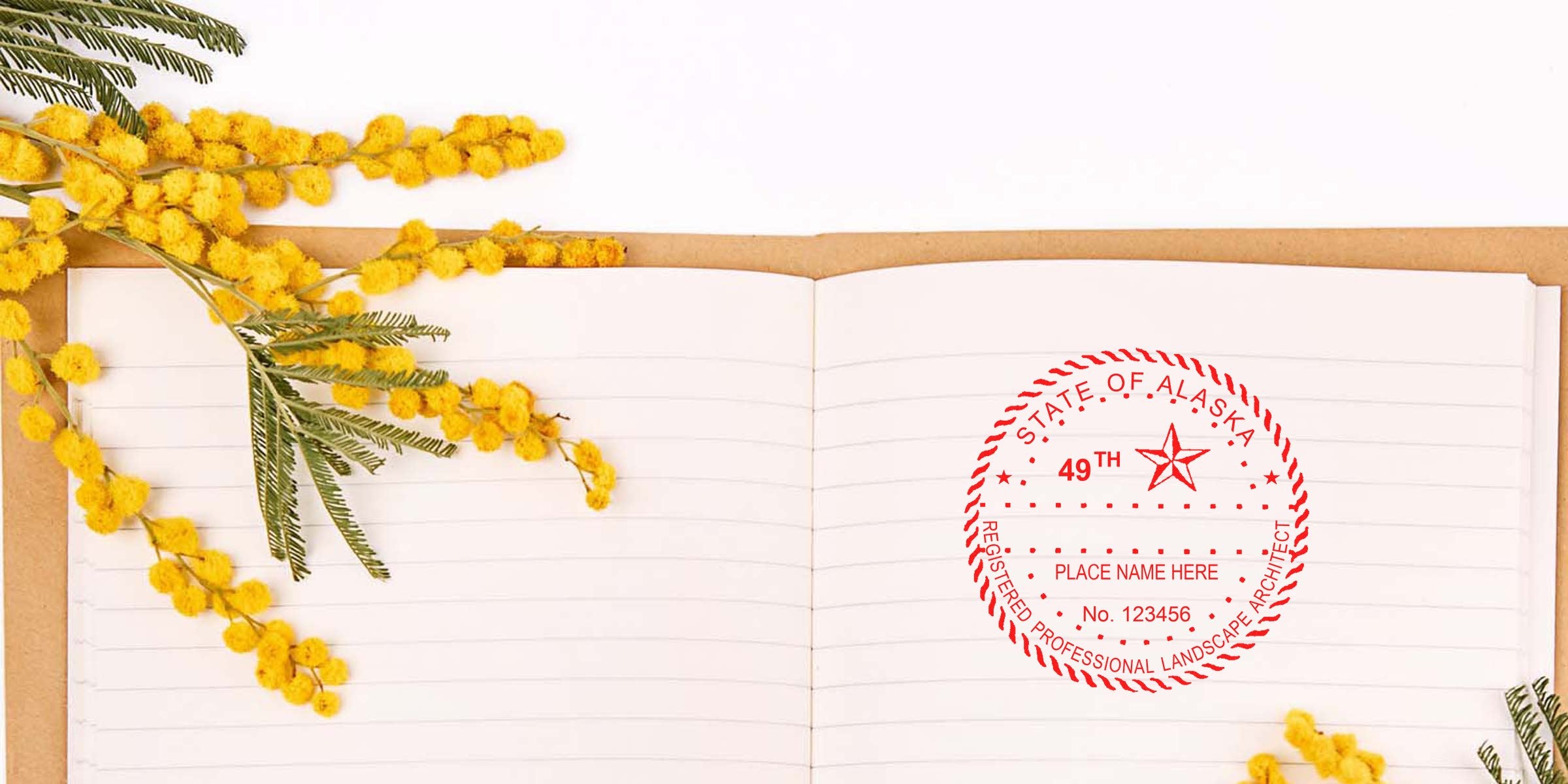 Open notebook with yellow mimosa flowers and an Alaska Landscape Architect stamp template on white, showcasing Alaska landscape design.