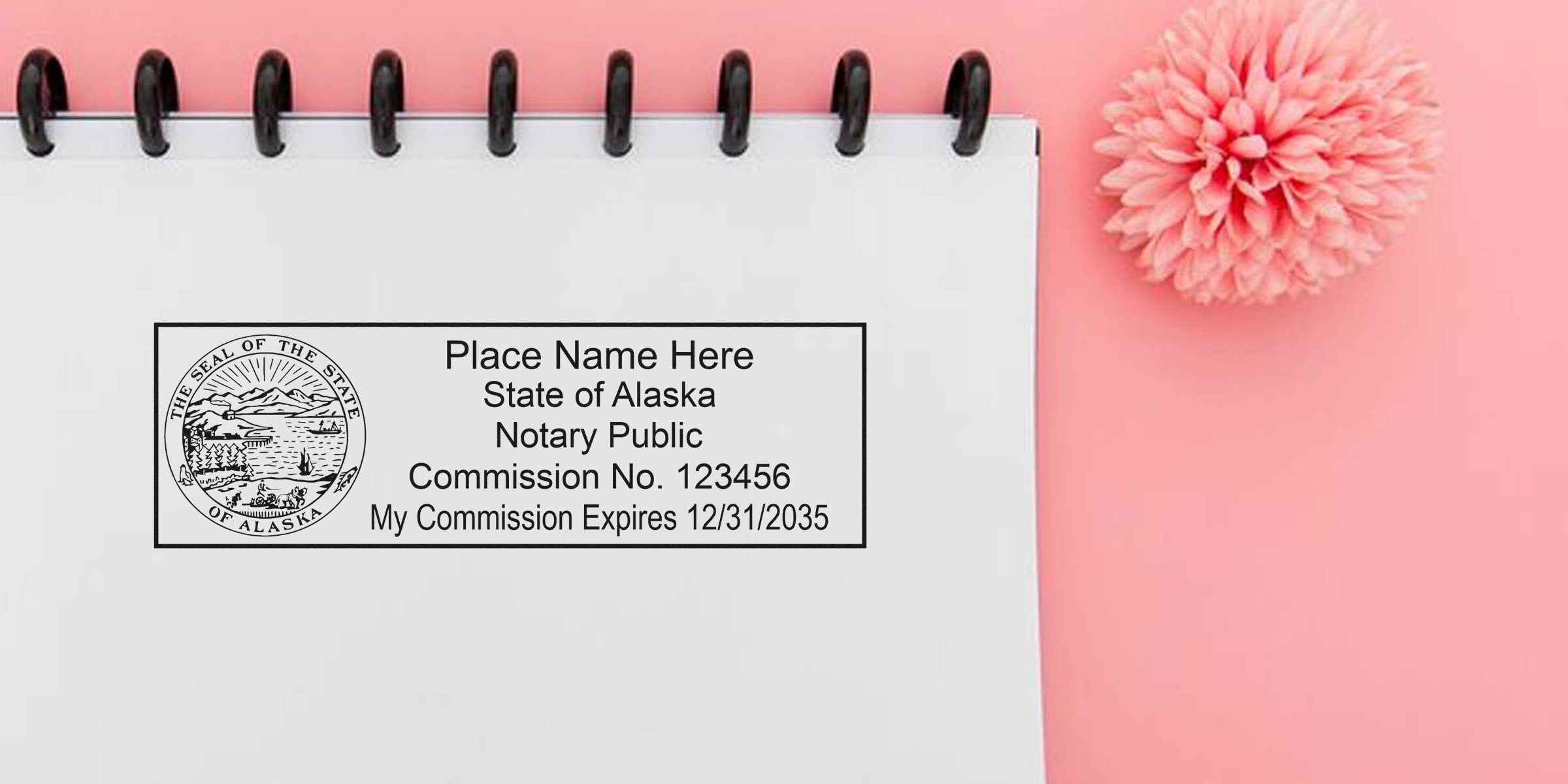 Alaska notary public stamp with commission number on white notebook, surrounded by notary supplies and tools, set against a pink background.