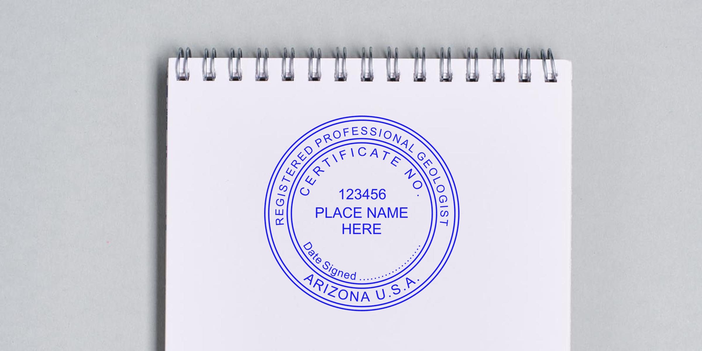 Arizona geologist stamp embossed on white spiral notebook with certificate number and location, using a professional embosser tool.