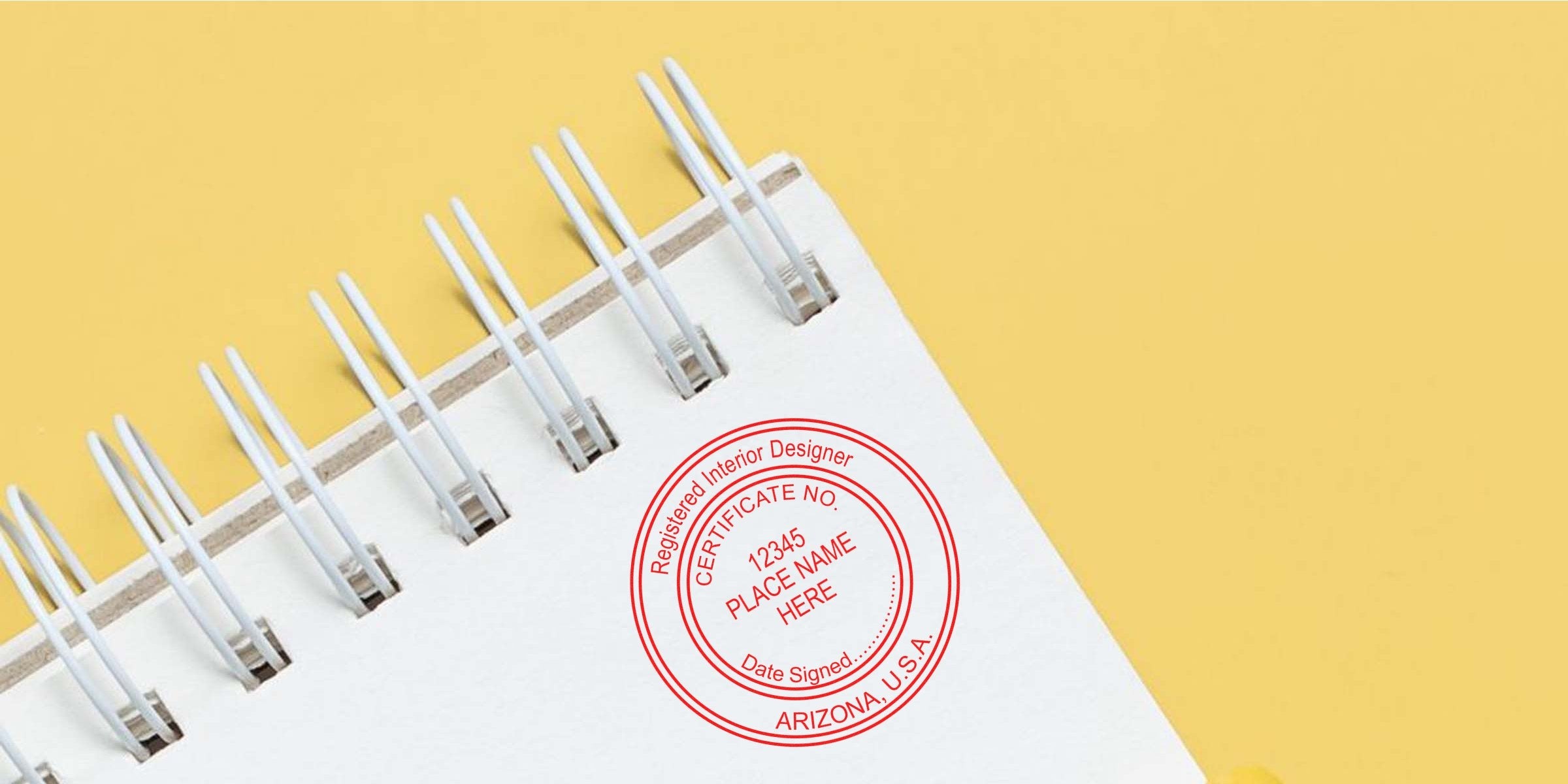 Custom stamp of a registered interior designer certificate on a spiral notebook page with a yellow background, showcasing Arizona interior design elements.