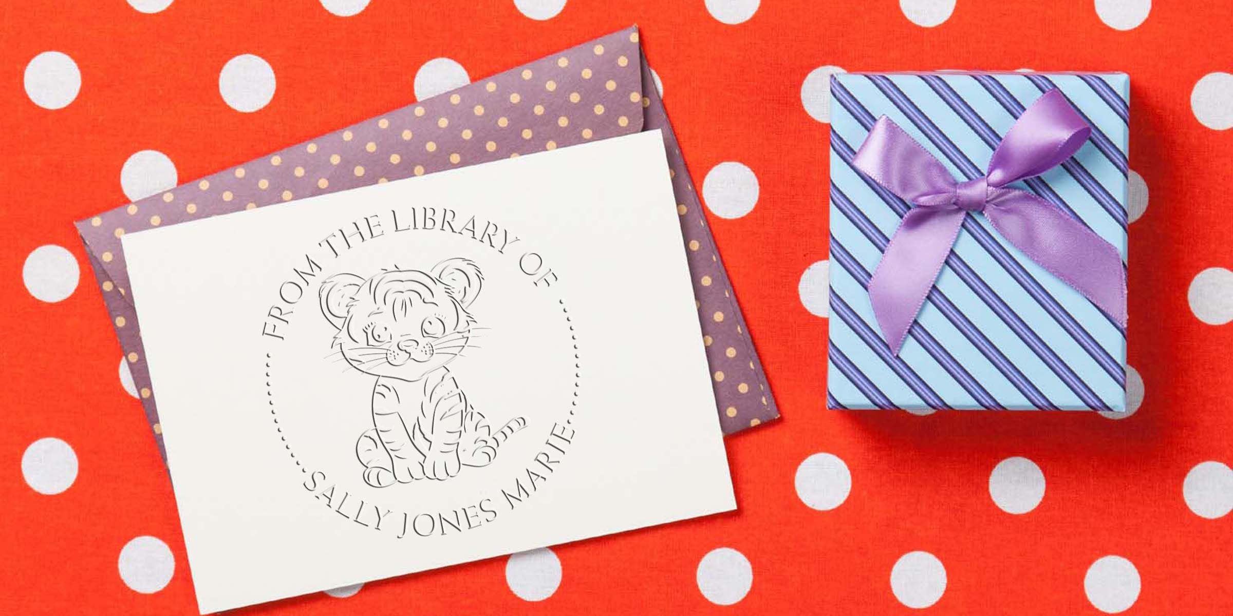 Personalized children’s bookplate with tiger illustration beside a blue wrapped gift with purple ribbon on a red polka dot background