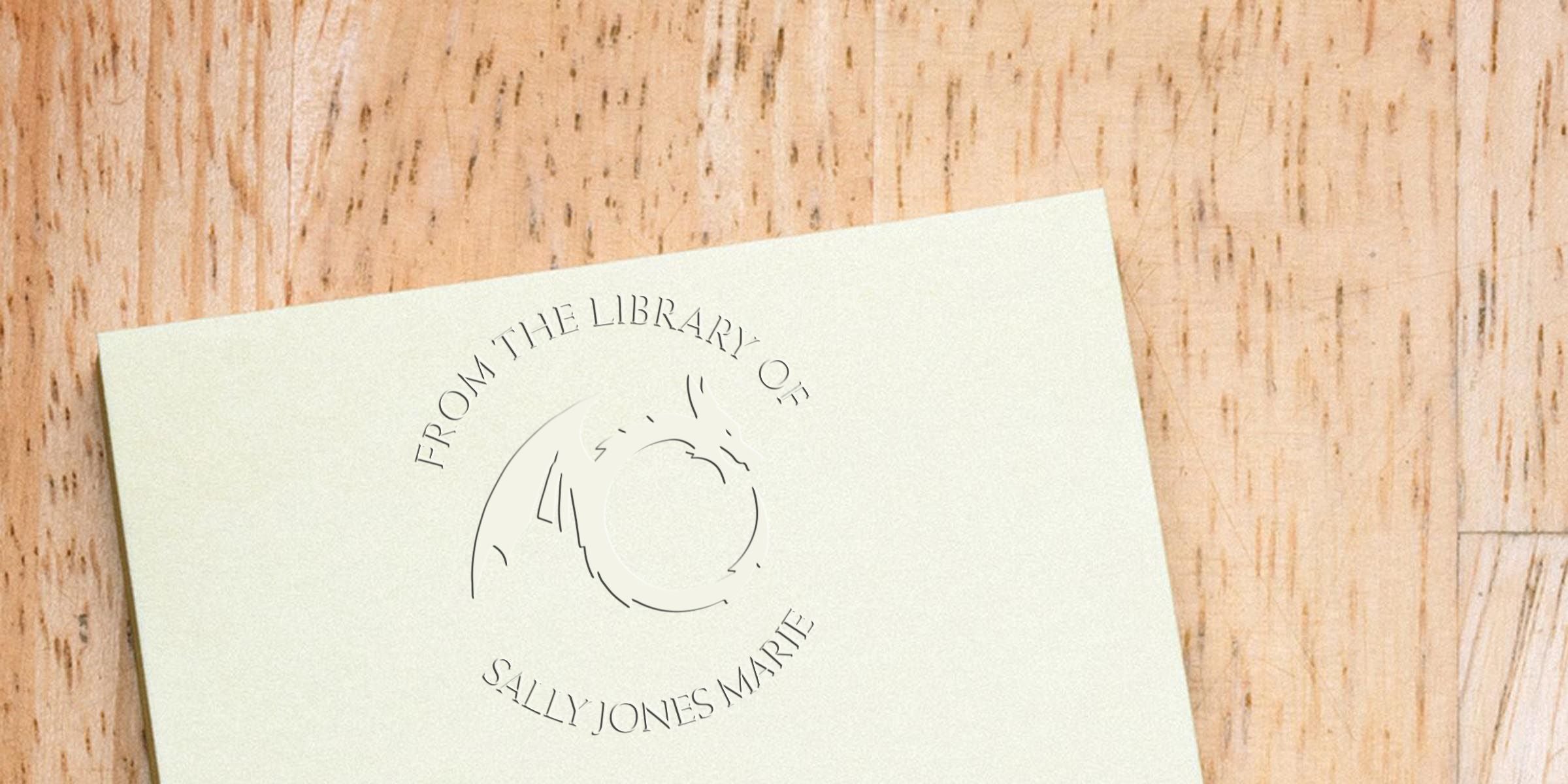 Embossed bookplate card reading “From the Library of Sally Jones Marie” on a light wooden surface