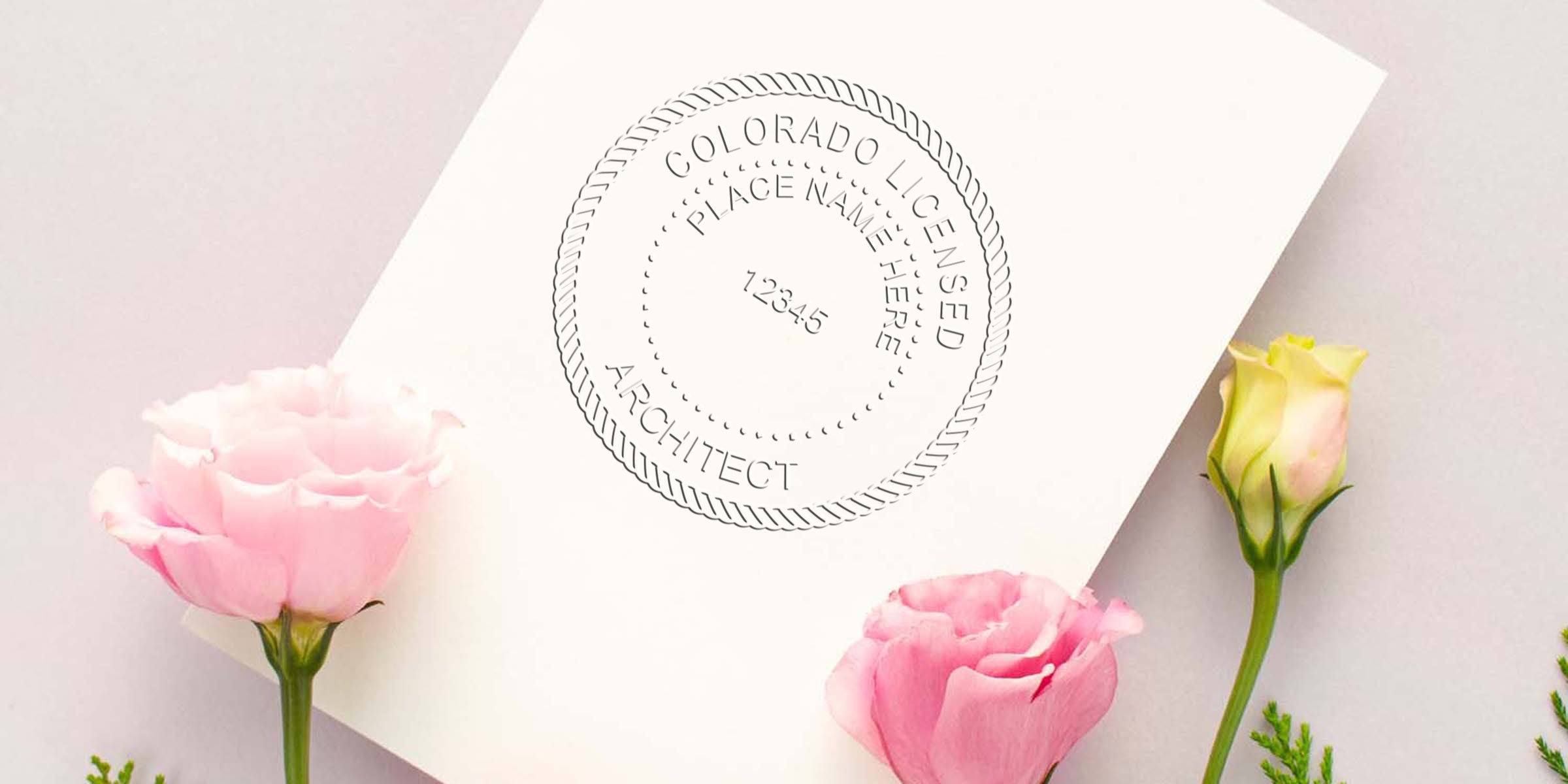 Colorado architect stamp on white paper with pink and yellow flowers, emphasizing the cost and value of a Colorado architect stamp.