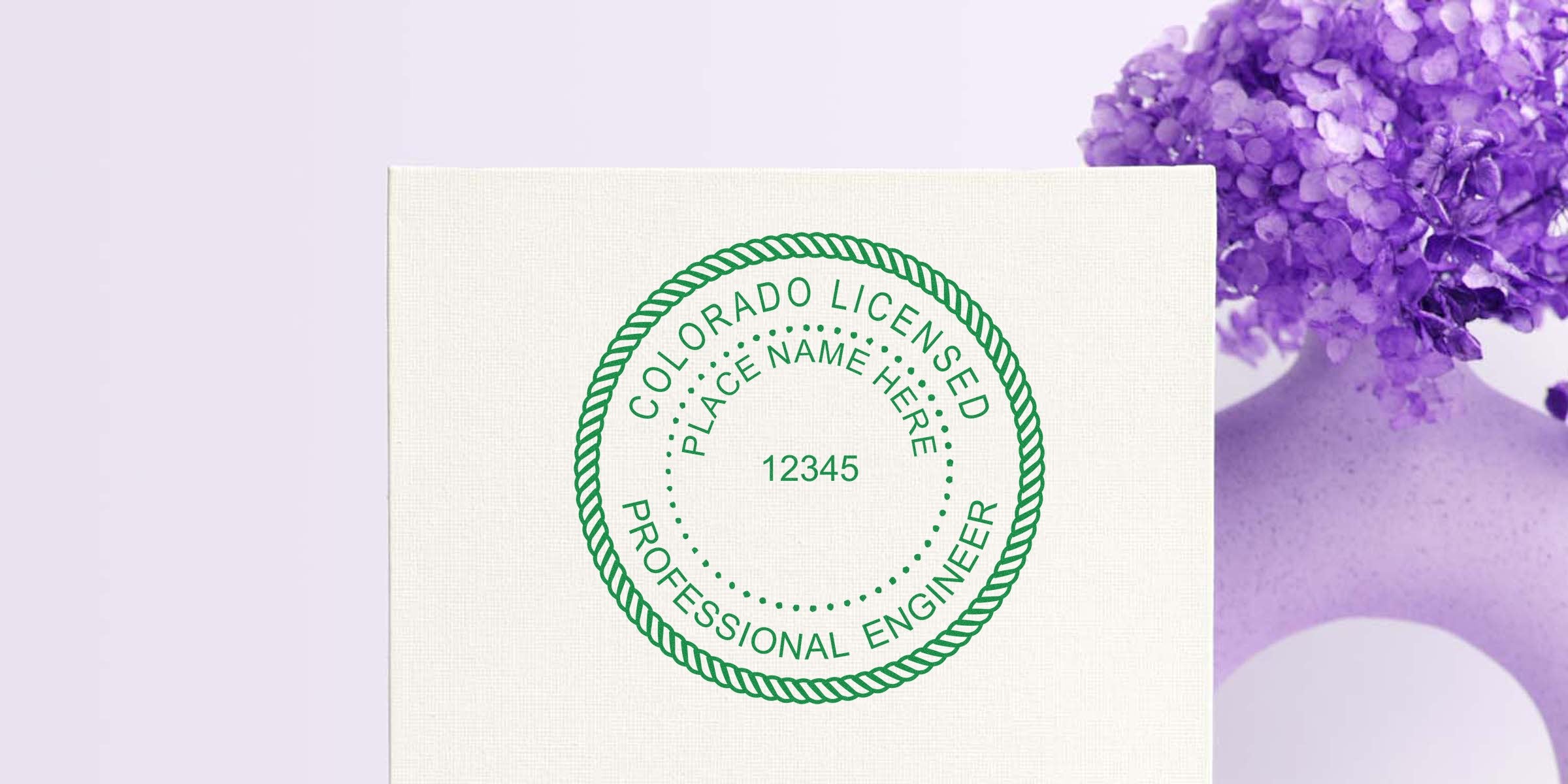 Green Colorado engineer stamp on white canvas next to a purple flower vase, indicating engineer approval.