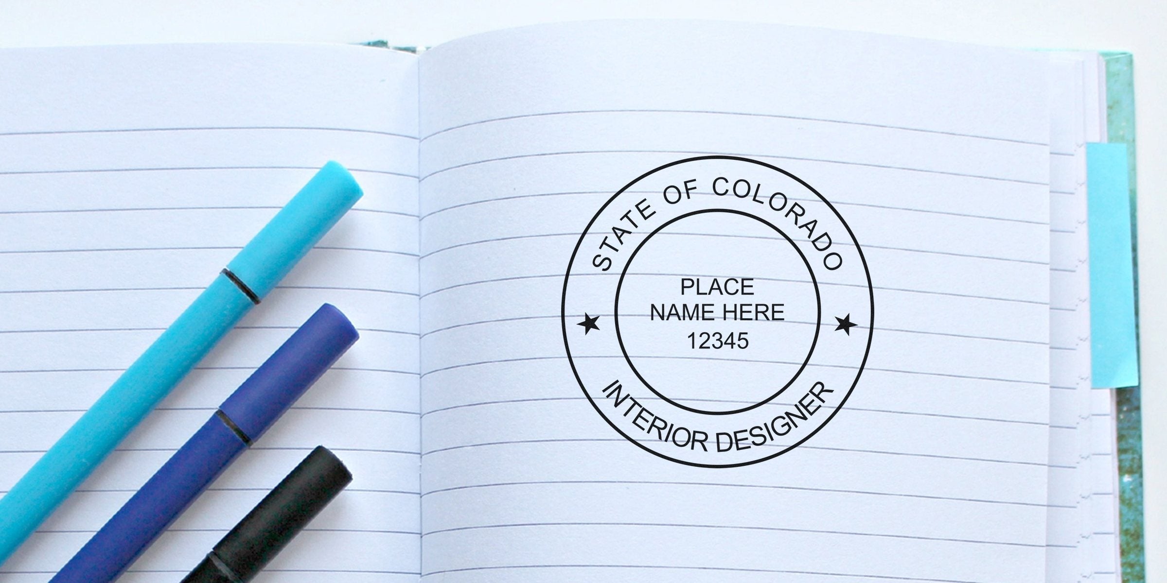 Notebook with Colorado interior design seal, surrounded by colorful pens, displaying embossing tips.