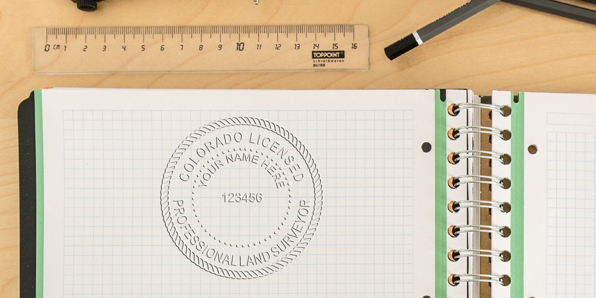 Custom Colorado land surveyor stamp and personalized stamp on graph paper with ruler and pen.