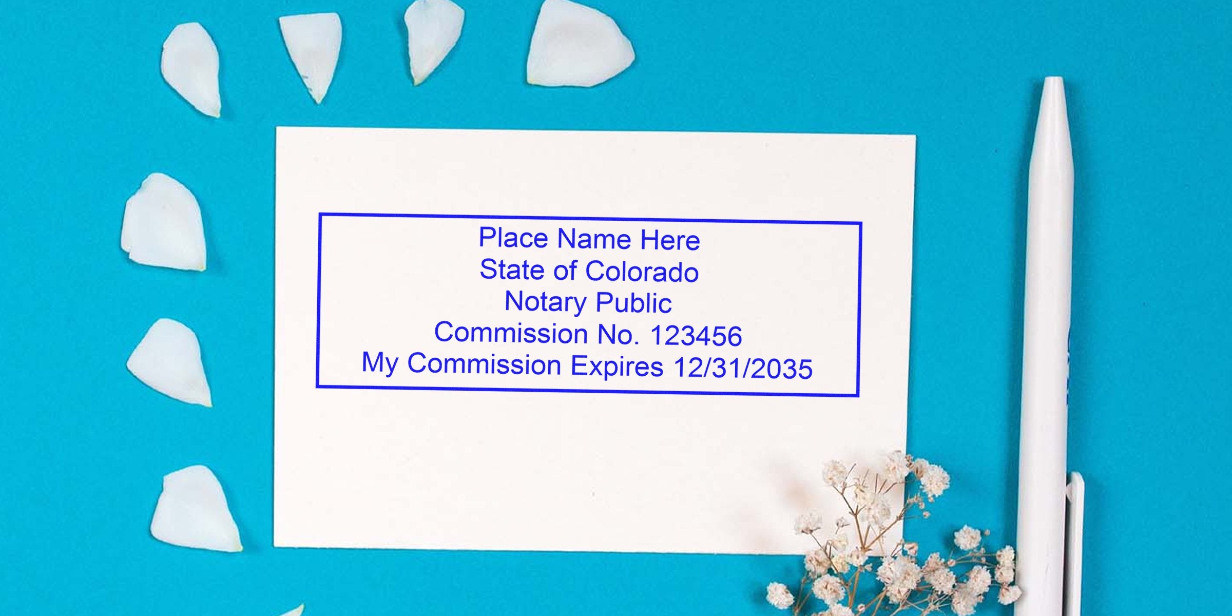 Colorado notary commission certificate with pen and flower petals on blue background, showcasing notary supplies and self-inking stamps.