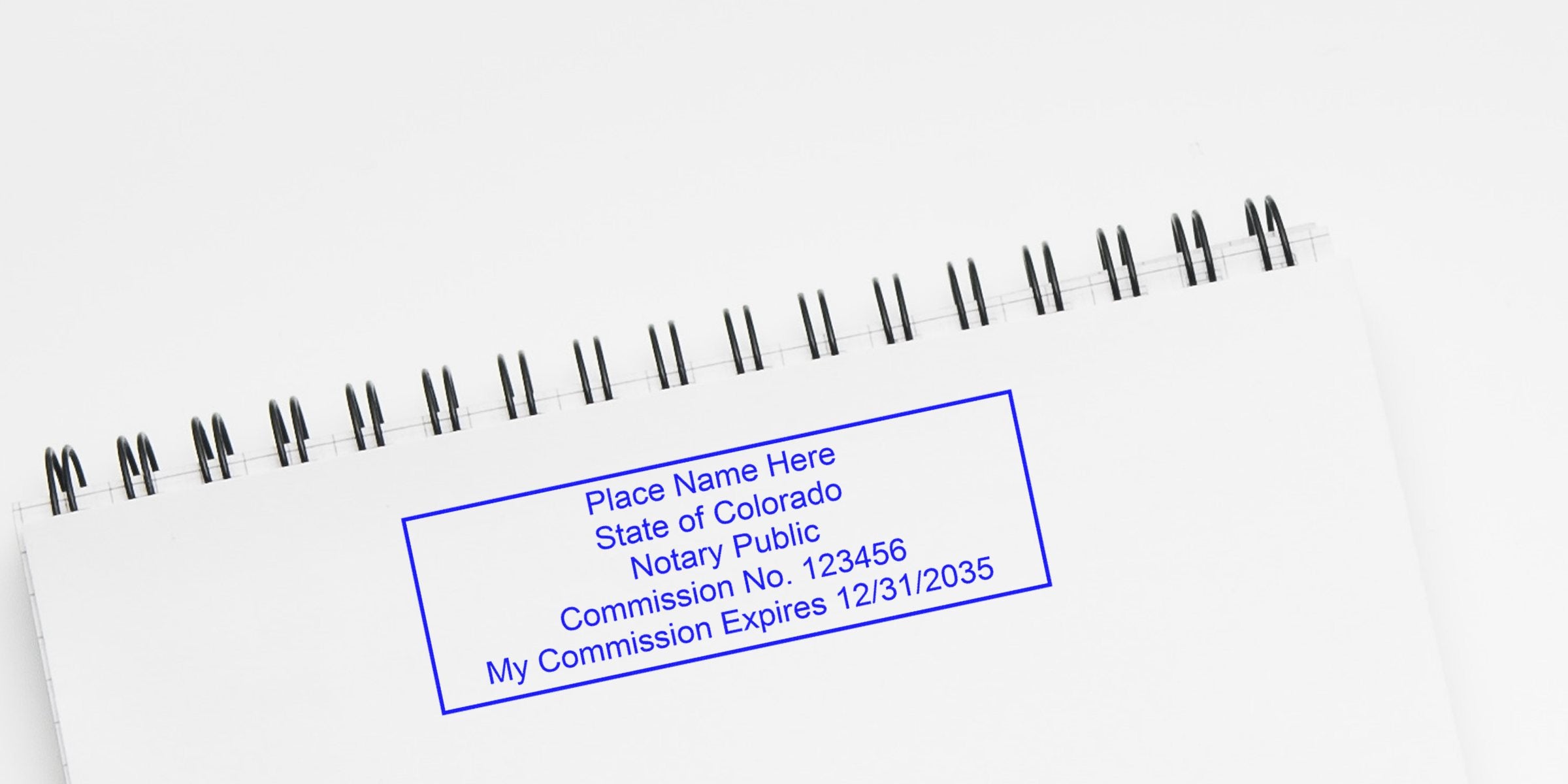 Colorado notary seal stamped on a spiral notebook, displaying commission number and expiration date, showcasing different notary stamp styles.
