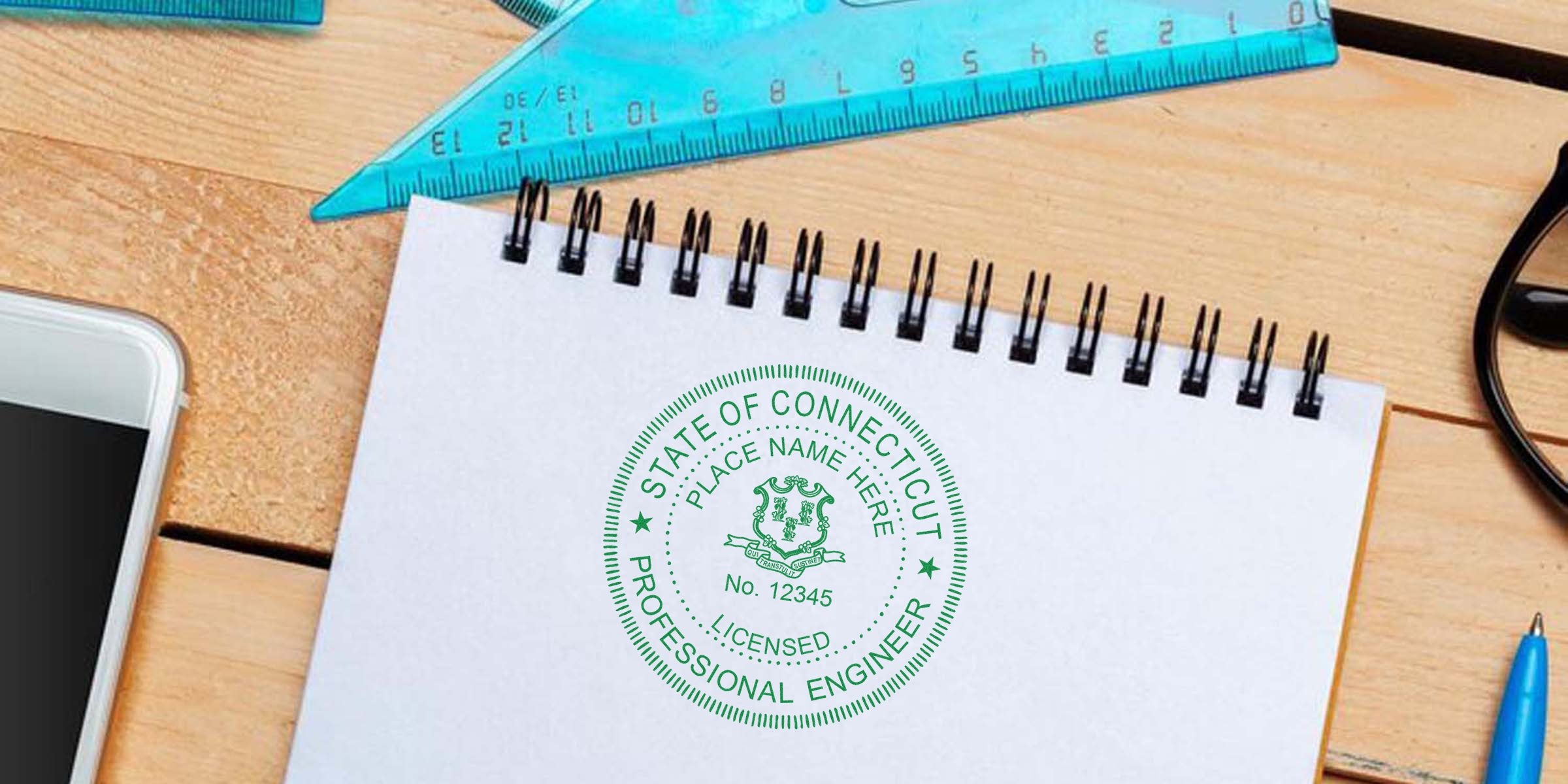 Connecticut engineer stamp and professional license seal on notebook with drafting tools, smartphone, and engineer embosser in Connecticut.
