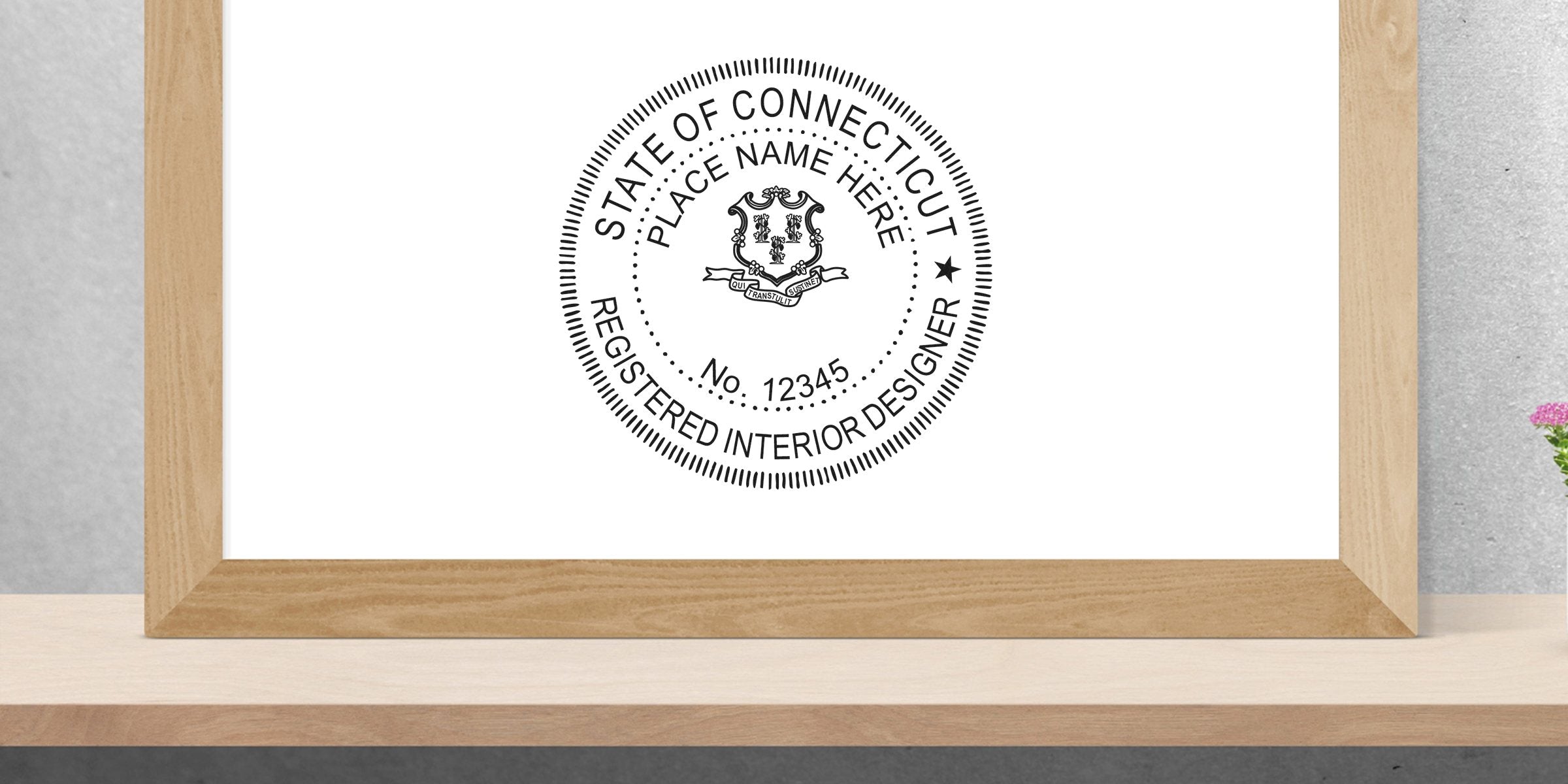 Framed Connecticut interior designer license seal on wooden shelf with flowers, showcasing Connecticut stamp requirements.