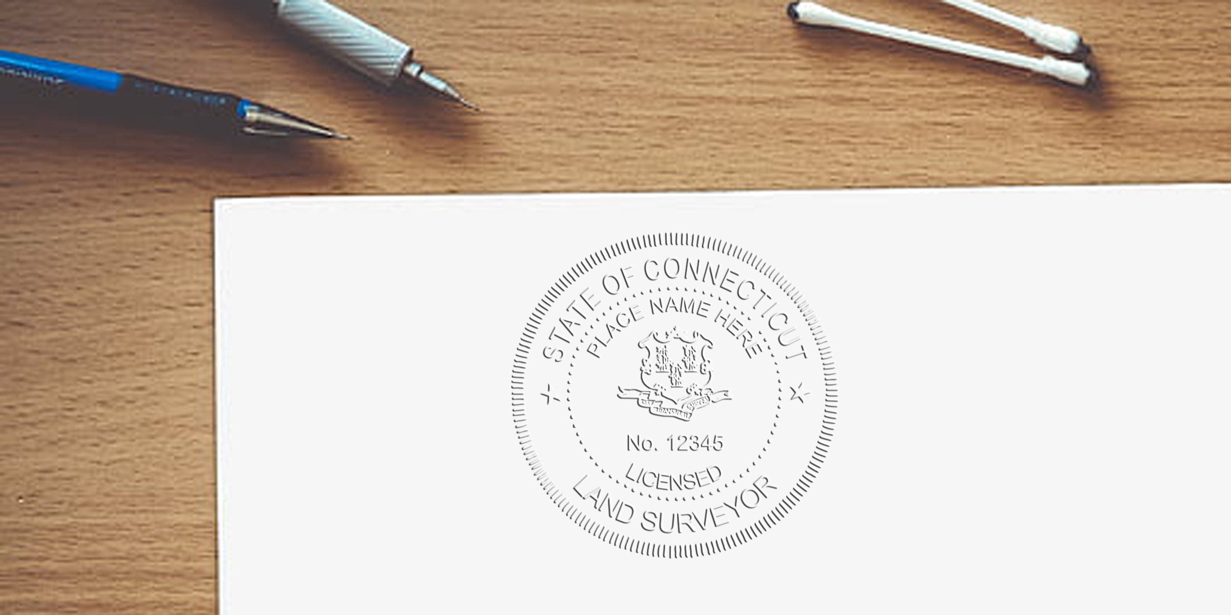 Connecticut land surveyor stamp embossed on white paper with drafting pens on a wooden desk, highlighting surveyor stamp color tips.