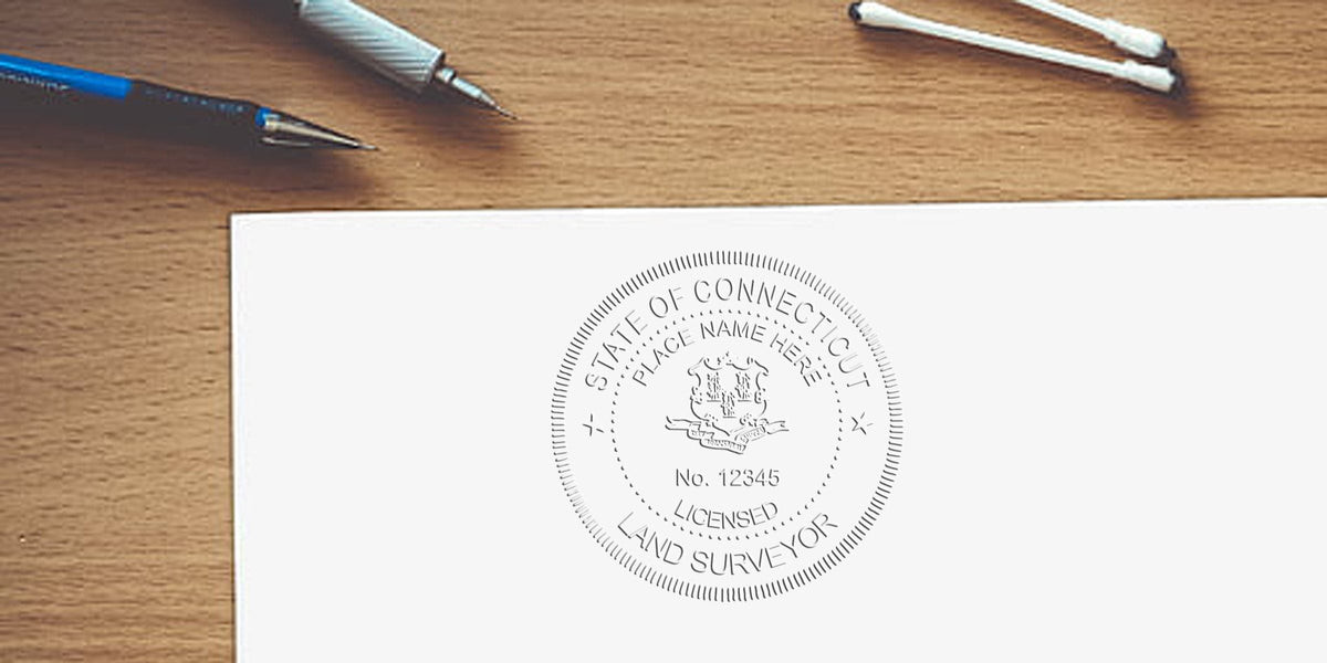 Connecticut land surveyor stamp embossed on white paper with drafting pens on a wooden desk, highlighting surveyor stamp color tips.