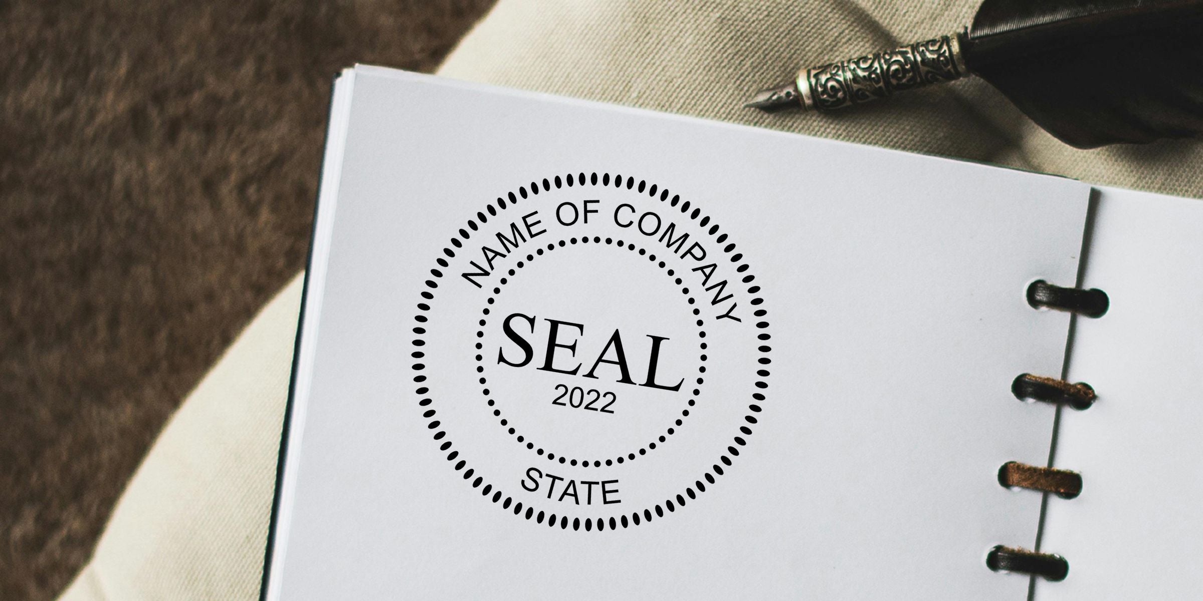 Open notebook featuring a custom company seal logo stamp with 2022 branding and an ornate pen for business branding presentation