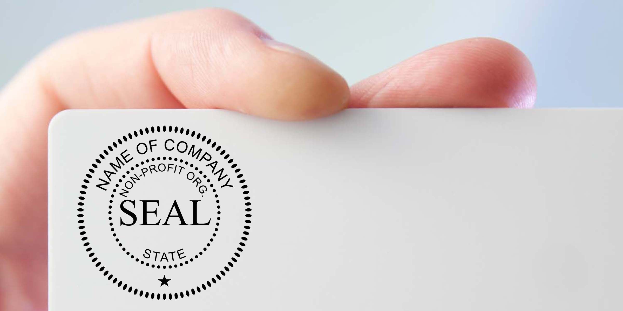 Close-up of a hand holding a white business card with a generic company seal logo and blank branding space