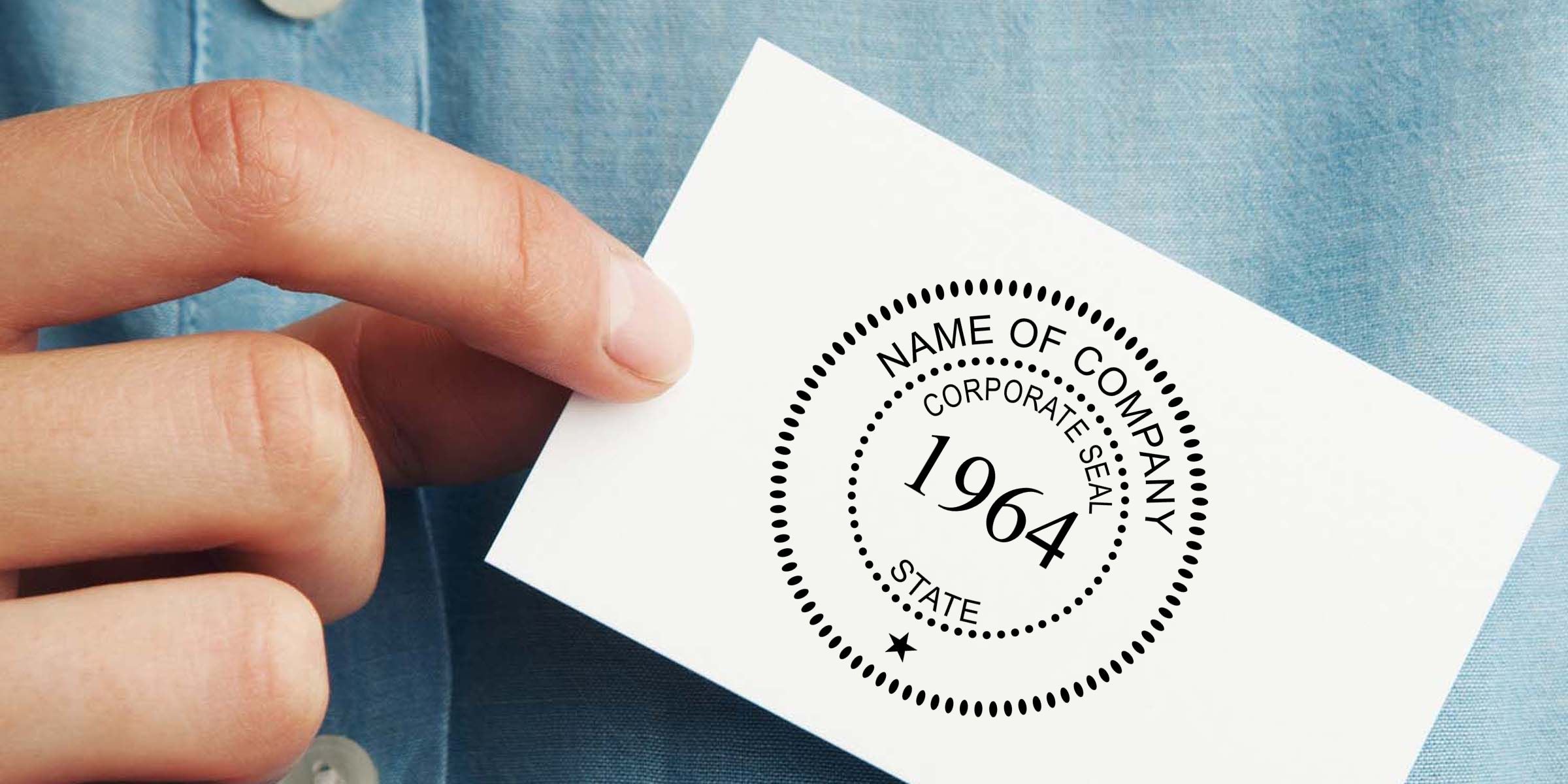Hand holding a business card with a corporate seal logo reading 1964 against a blue shirt background