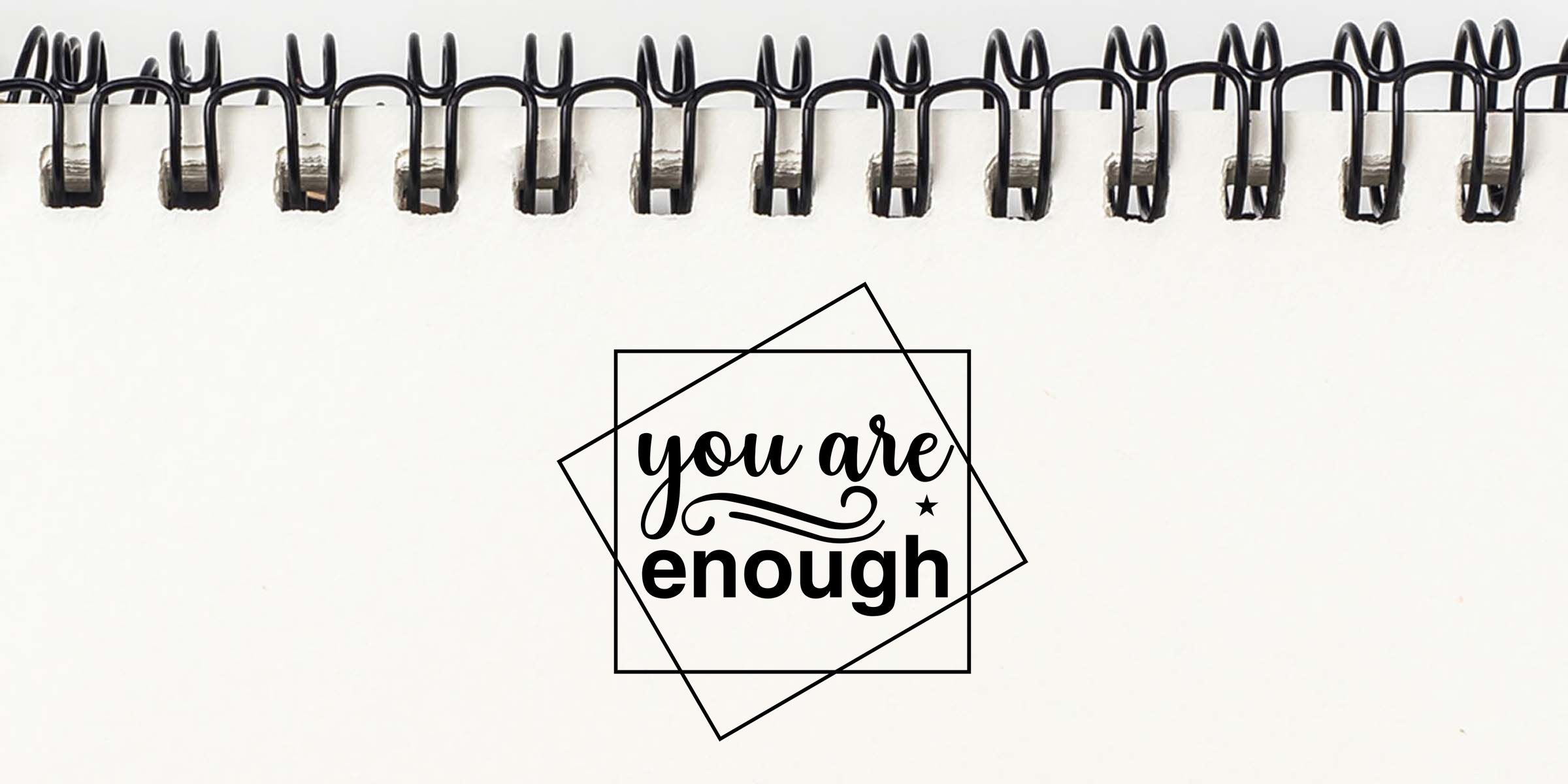 Minimalist spiral notebook page with motivational quote “you are enough” in black typography on a white background