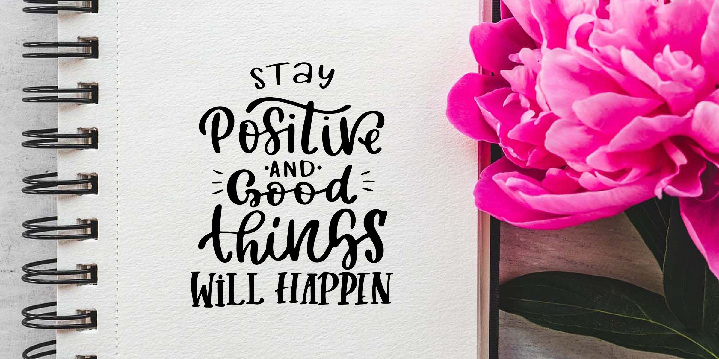 Inspirational notebook page with “Stay positive and good things will happen” quote beside bright pink peony flowers and spiral binding