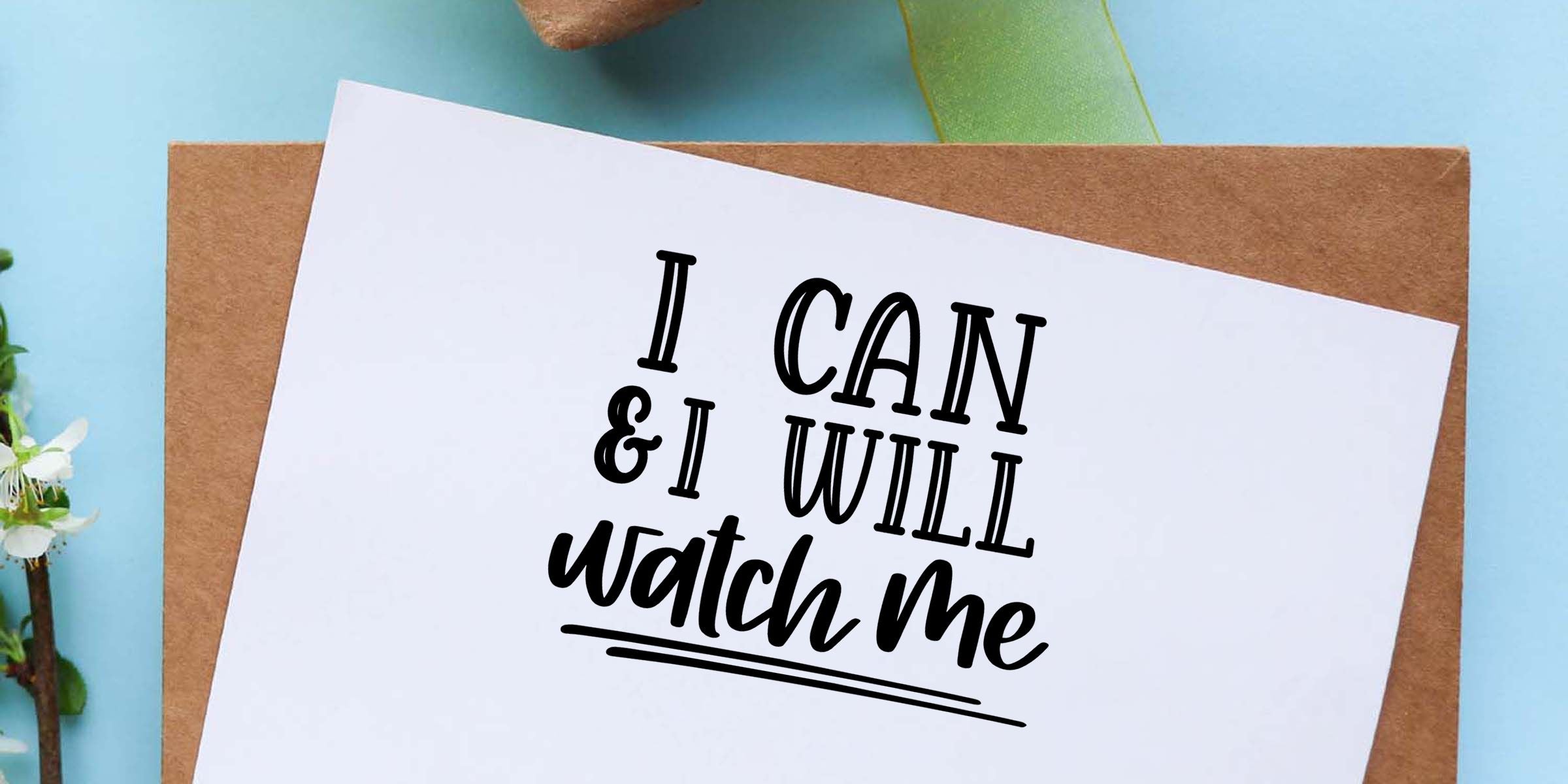 Inspirational quote card reading “I can & I will watch me” on white paper over a kraft envelope with blue background and ribbon accents