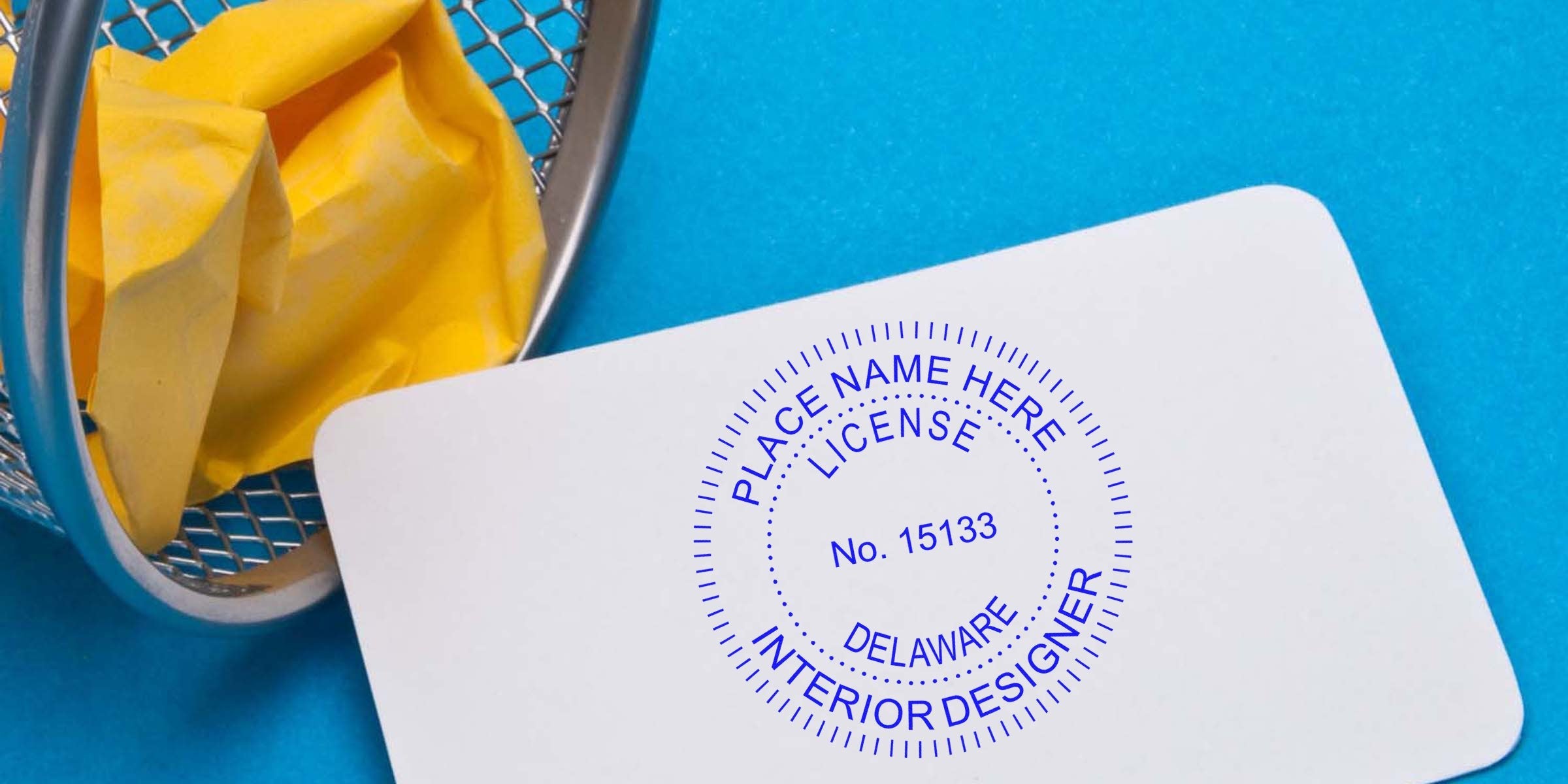 Delaware interior designer license card with stamp on yellow paper in trash bin against blue background, related to Delaware interior design licensing.
