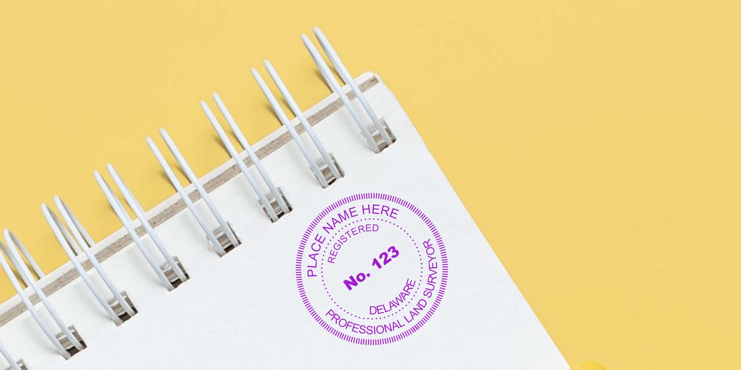 Delaware land surveyor renewal stamp on a spiral notebook with a yellow background, showing surveyor stamp tips.