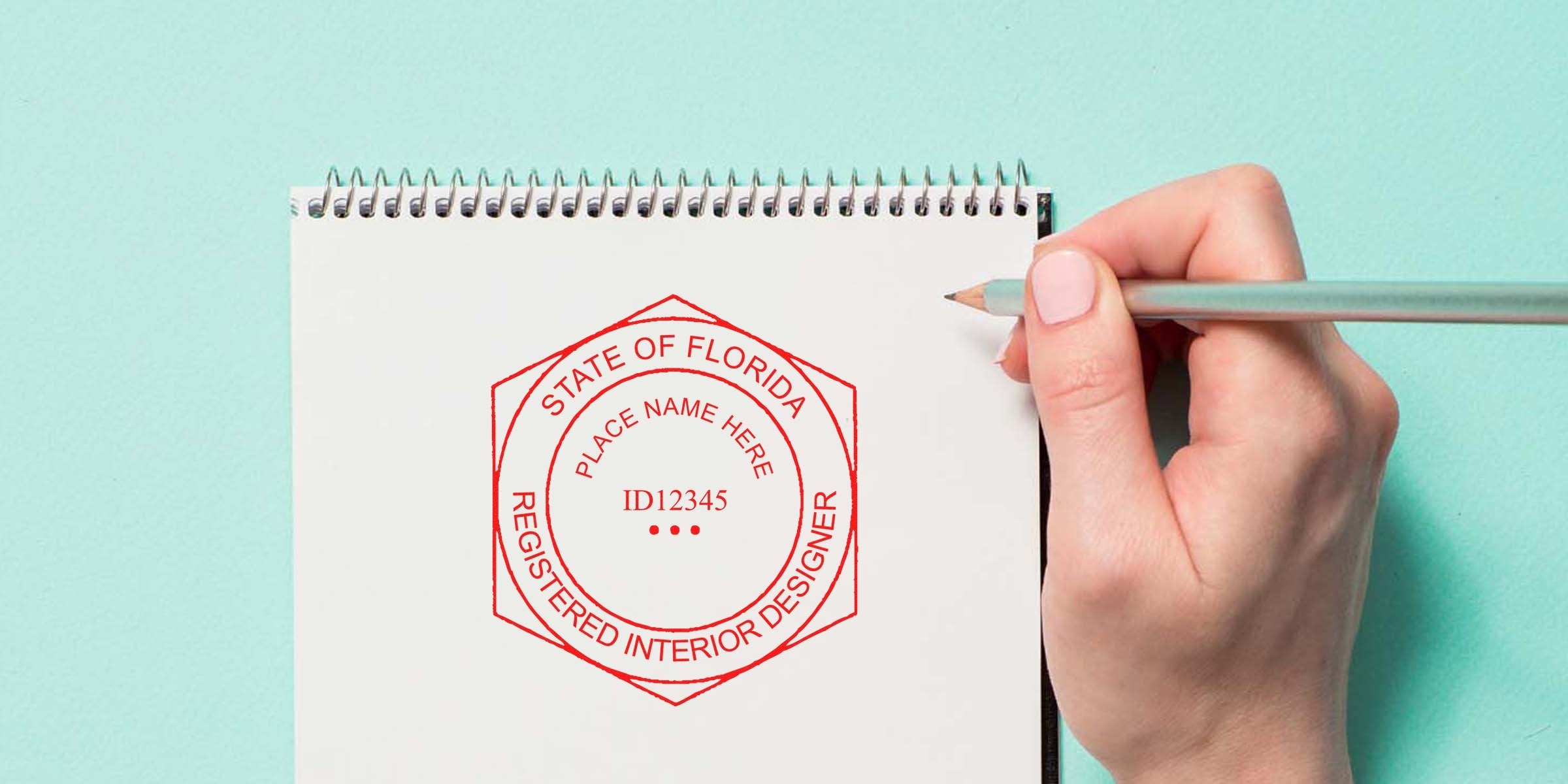 Hand holding pencil drawing Florida interior designer license stamp on notebook, showing certification and licensing requirements for interior design in Florida.