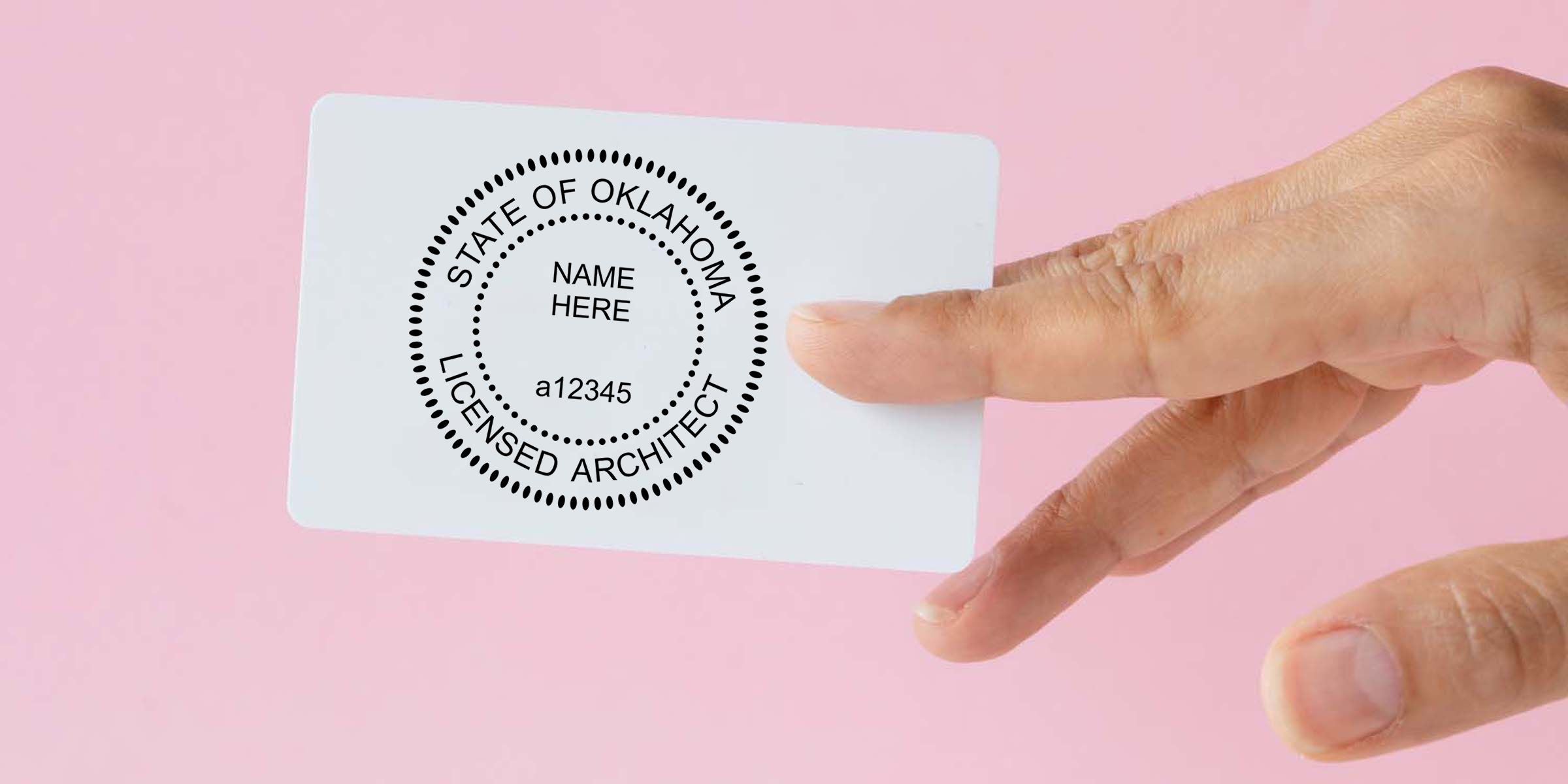 Hand holding white Oklahoma licensed architect ID card with circular seal, name placeholder, and ID number on pink background