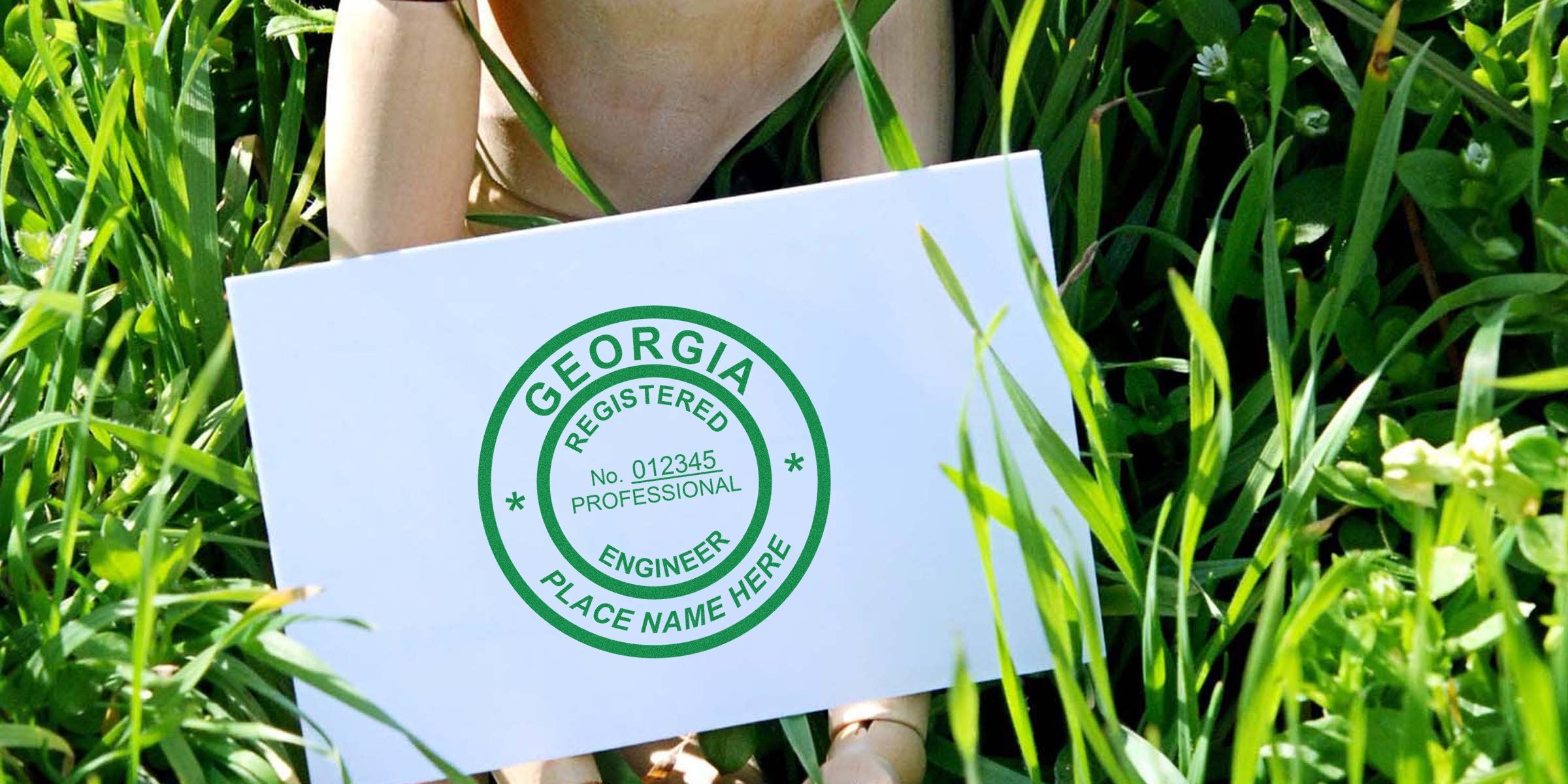 Georgia PE stamp on white card held against green grass, showing professional engineer seal.