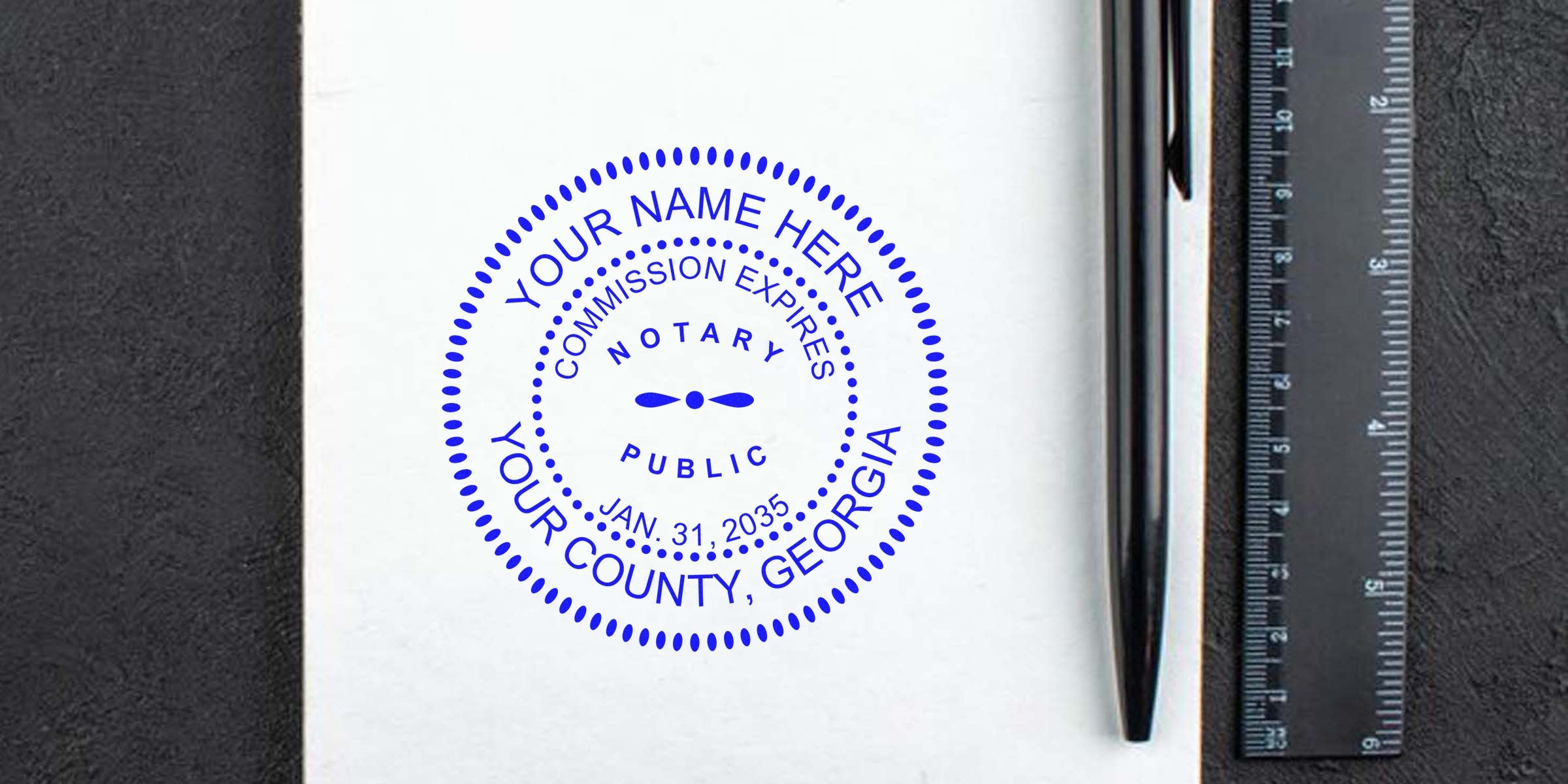 Blue Georgia notary seal on white paper with pen and ruler, trusted notary stamp for county commission, expires January 31, 2035.