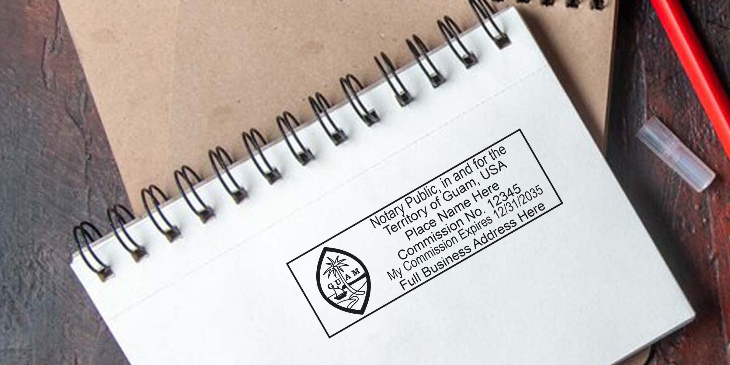 Self-inking Guam notary stamp on spiral notebook displaying commission number and business address.