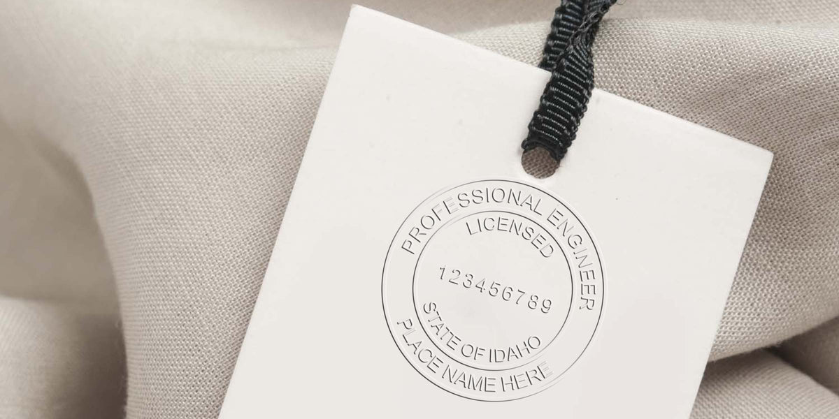 PE Stamp Idaho with licensed engineer badge, state seal, and black string on beige fabric. Order your PE Stamp today.