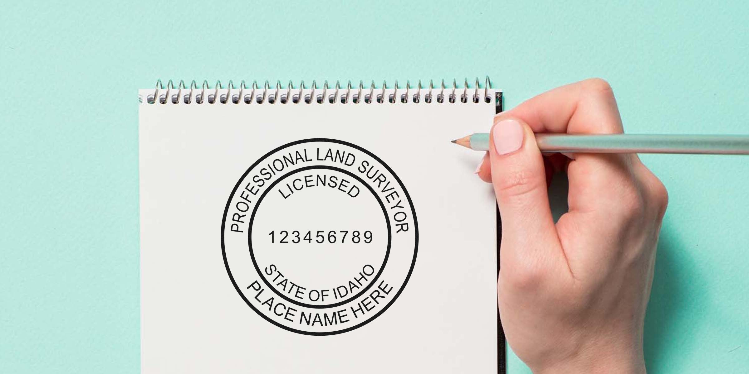 Idaho land surveyor seal with license number on white notepad, hand holding pencil, showing Idaho land surveyor seals and seal requirements.