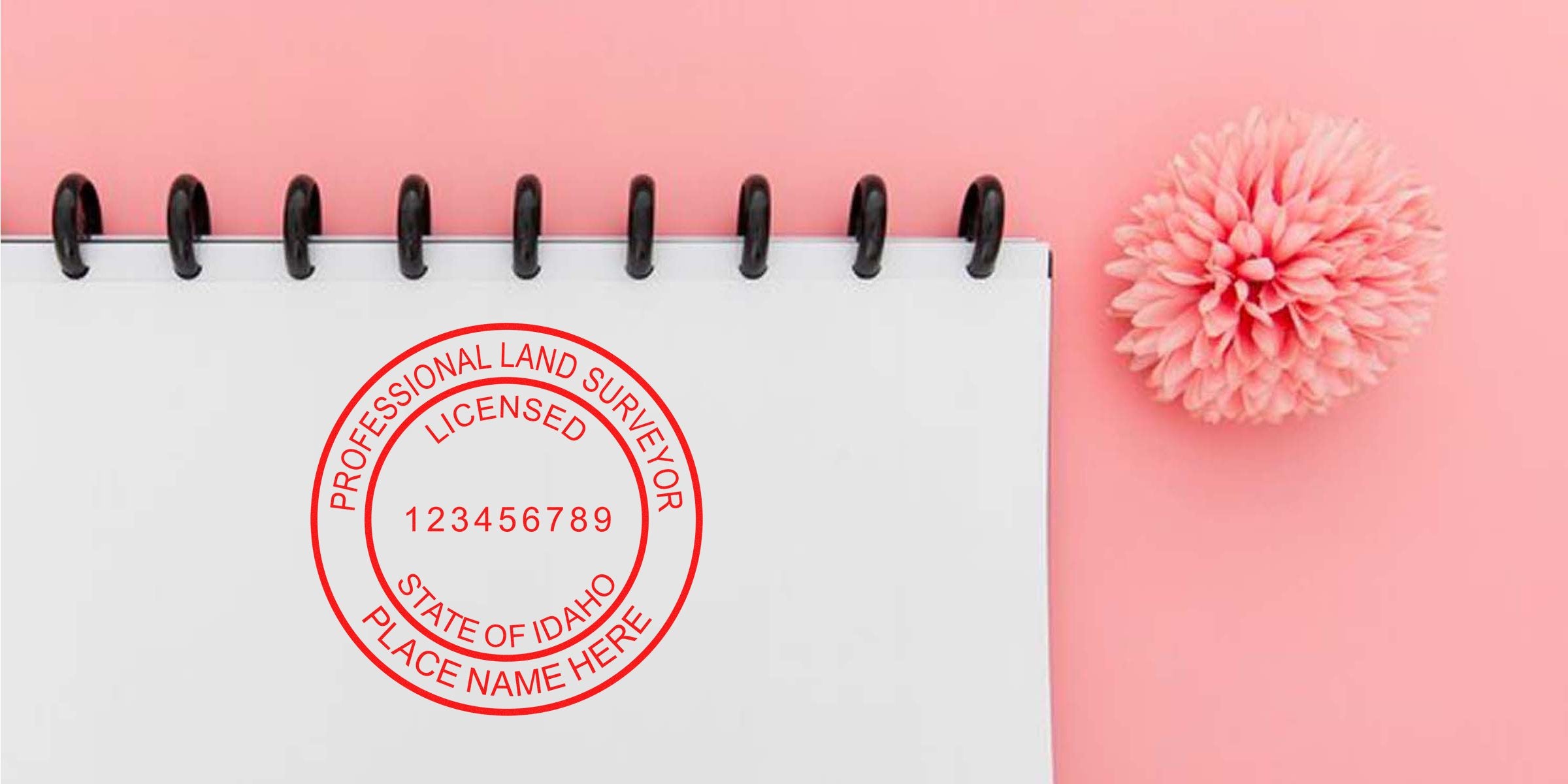 Idaho land surveyor stamp on notebook with pink background and flower, meeting all surveyor stamp requirements.