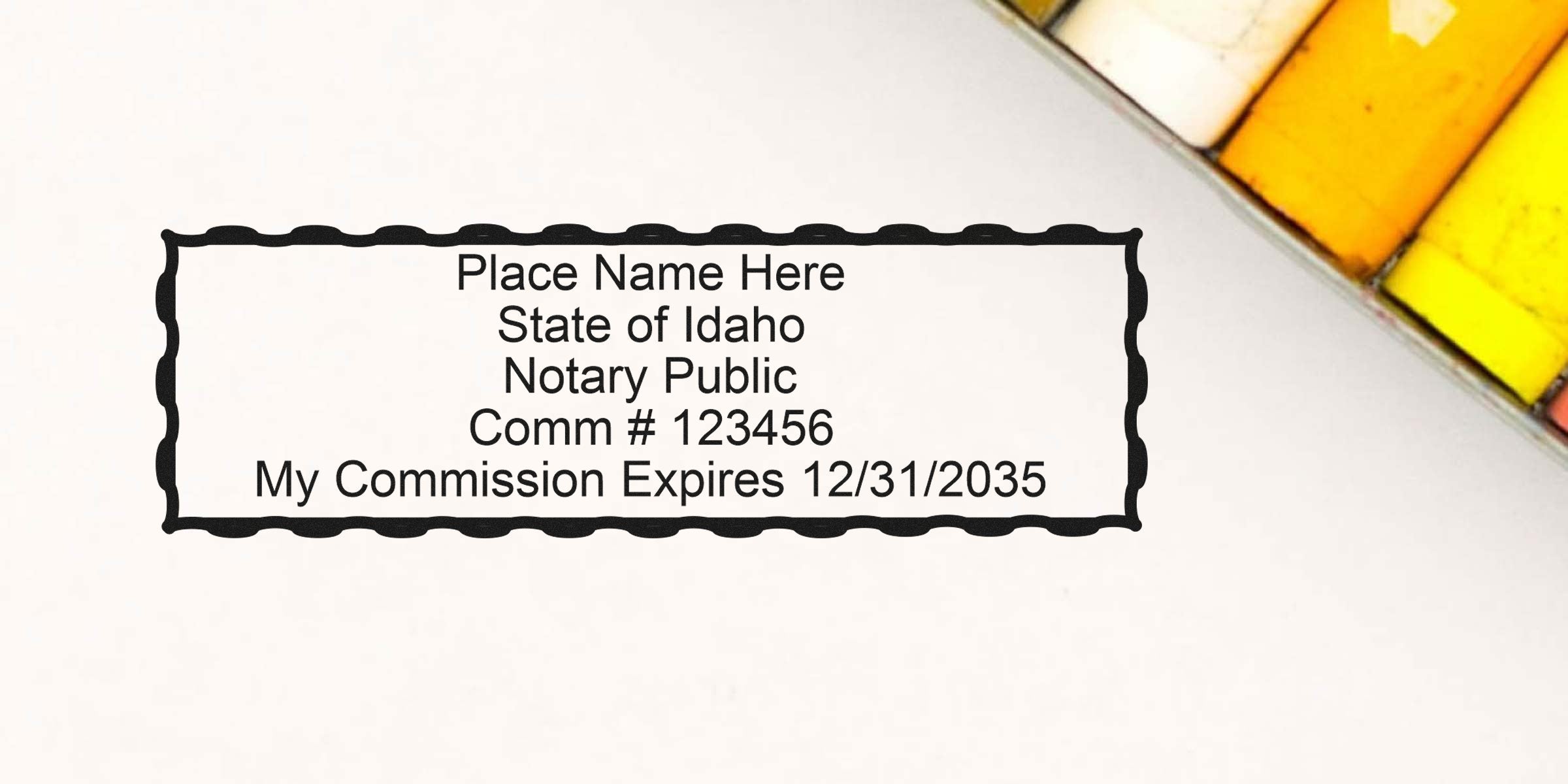 Perfect Notary Seal Idaho showing a notary stamp with commission number and expiration date on white paper next to colored pencils.