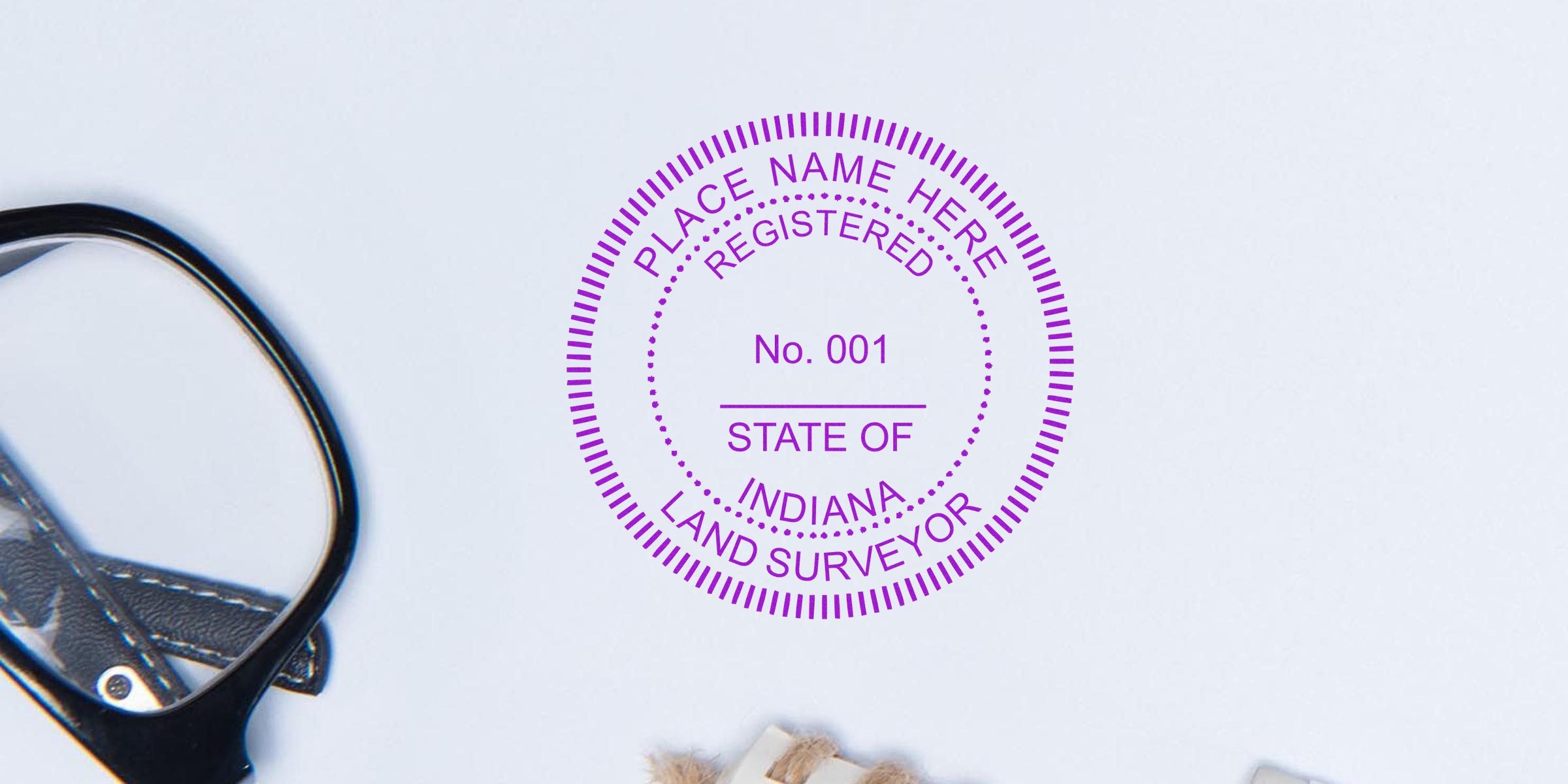 Indiana land surveyor stamp with registration 001 on white background next to eyeglasses and rope knot, illustrating Indiana land surveyor rules and stamp requirements.
