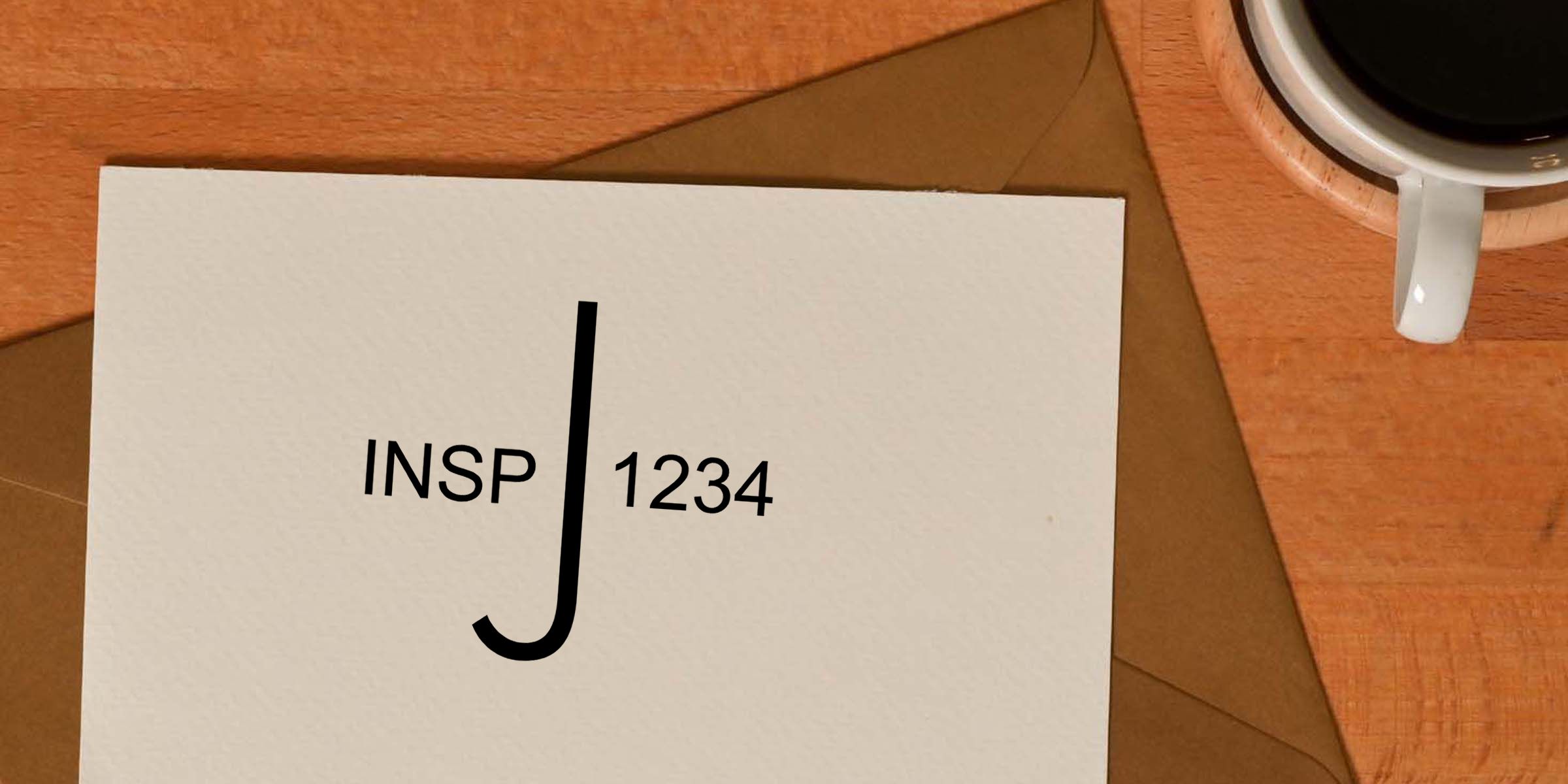 Minimalist white card with black J monogram and INSP 1234 on a wooden desk beside an envelope and coffee cup