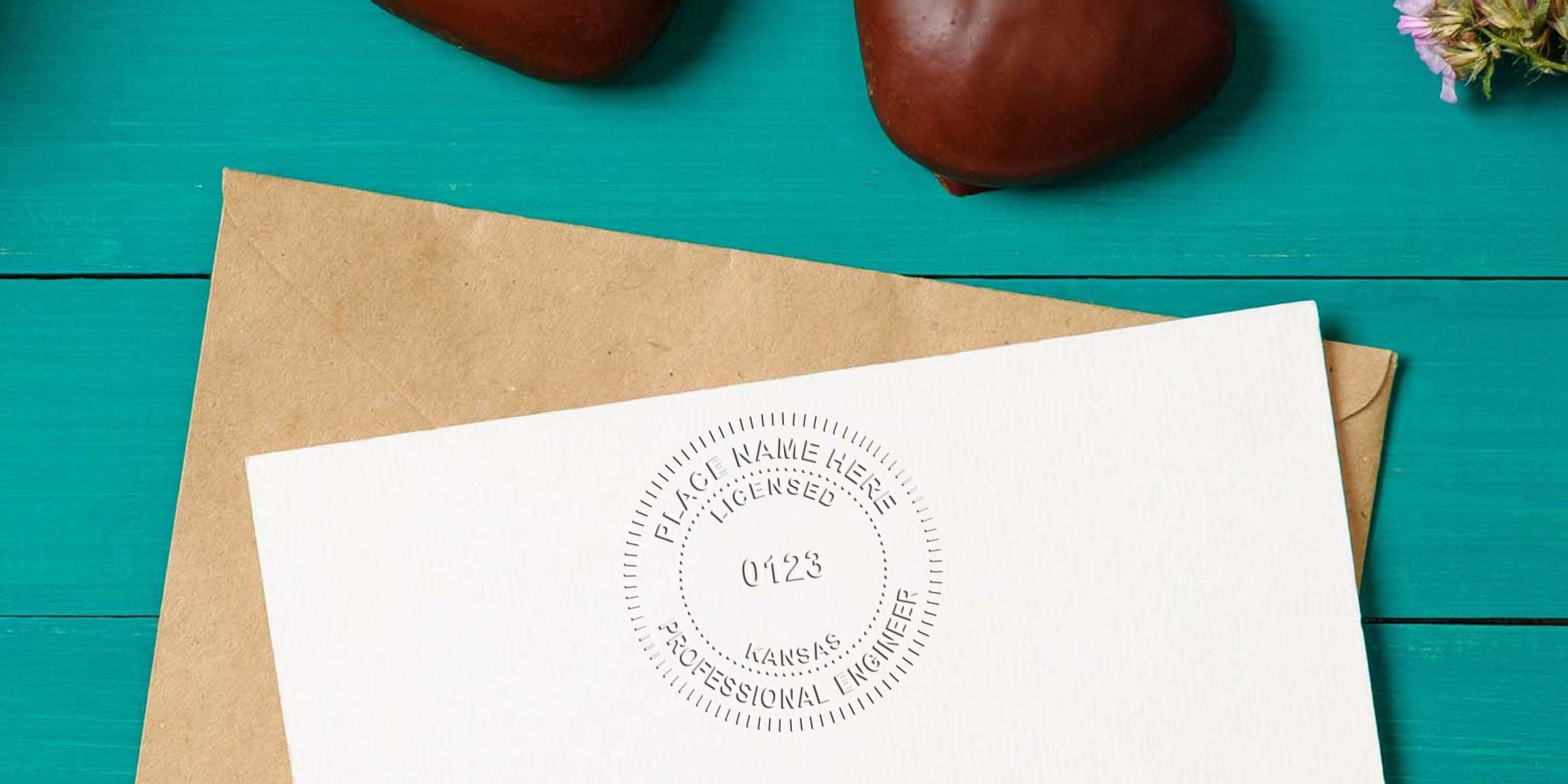 Professional Engineer Stamp Kansas on white paper with brown envelope on turquoise wooden table. Buy Engineer Stamp Kansas now.