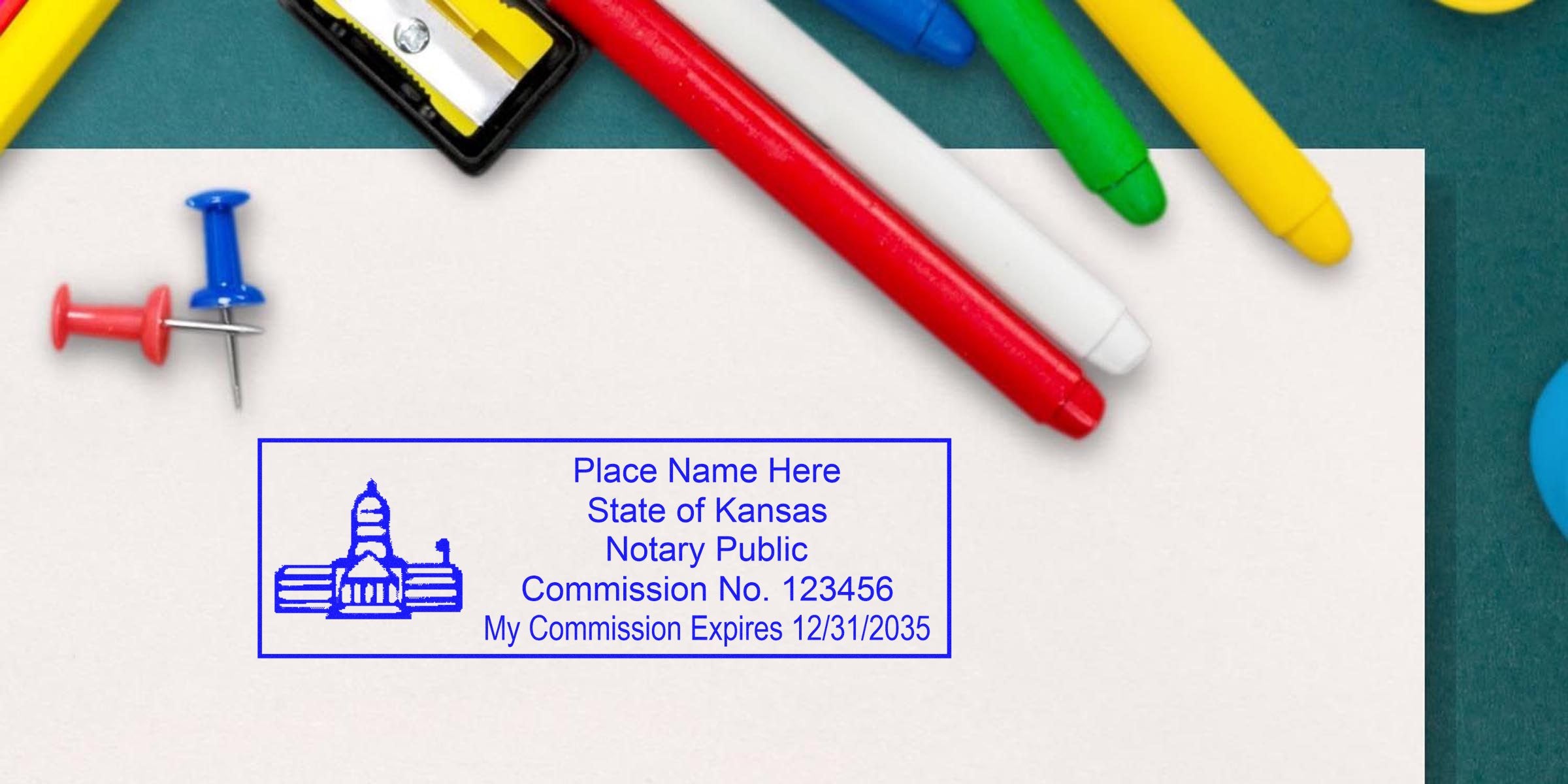 Kansas notary stamp with commission number and expiry on white paper, surrounded by colorful markers and push pins, highlighting Kansas notary seal size and key notary supplies.
