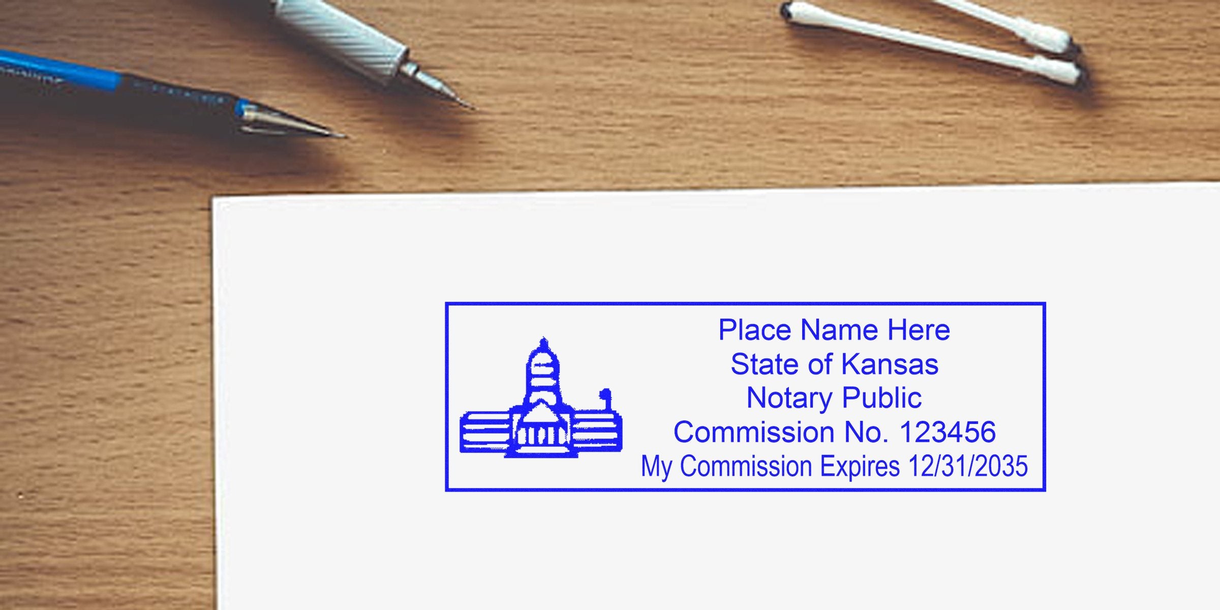 Kansas notary stamp with commission number and expiration date on wooden desk, next to a self-inking stamp, pens, and cotton swabs.