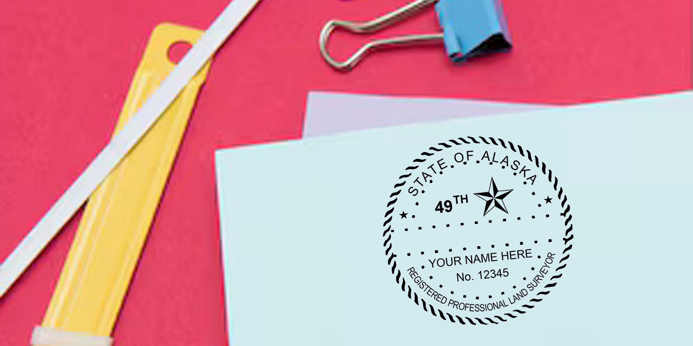 Alaska State 49th registered professional land surveyor certificate with binder clip on a red background