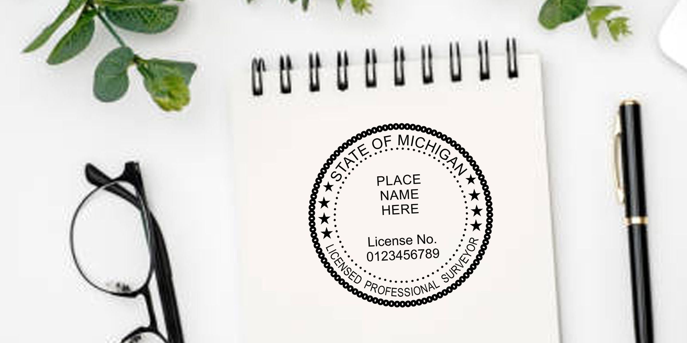 State of Michigan licensed professional surveyor stamp on a spiral notebook with eyeglasses, pen, and green plant leaves on a clean desk