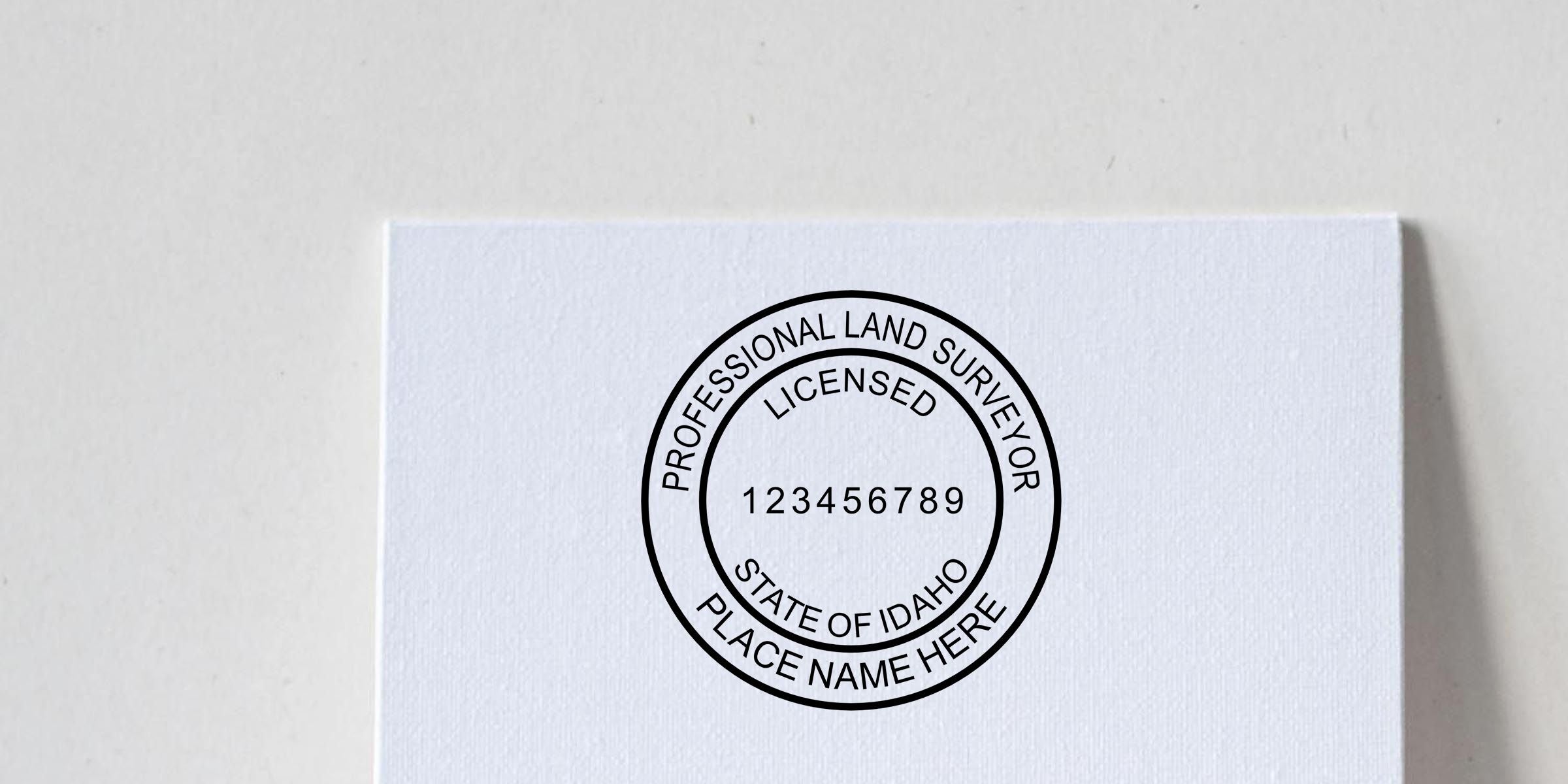 White paper with a professional land surveyor licensed stamp from the State of Idaho, featuring circular seal text and license number 123456789