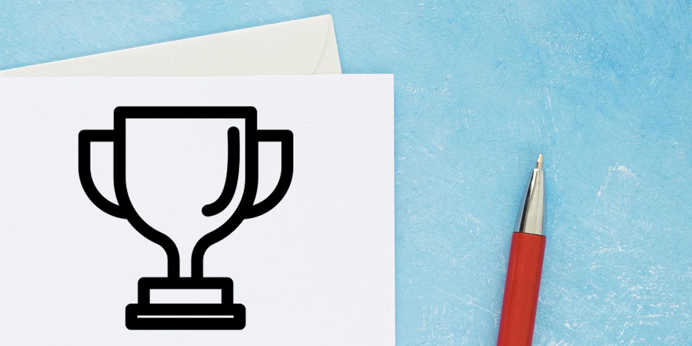 Trophy award icon printed on white paper beside a red pen on a blue textured background