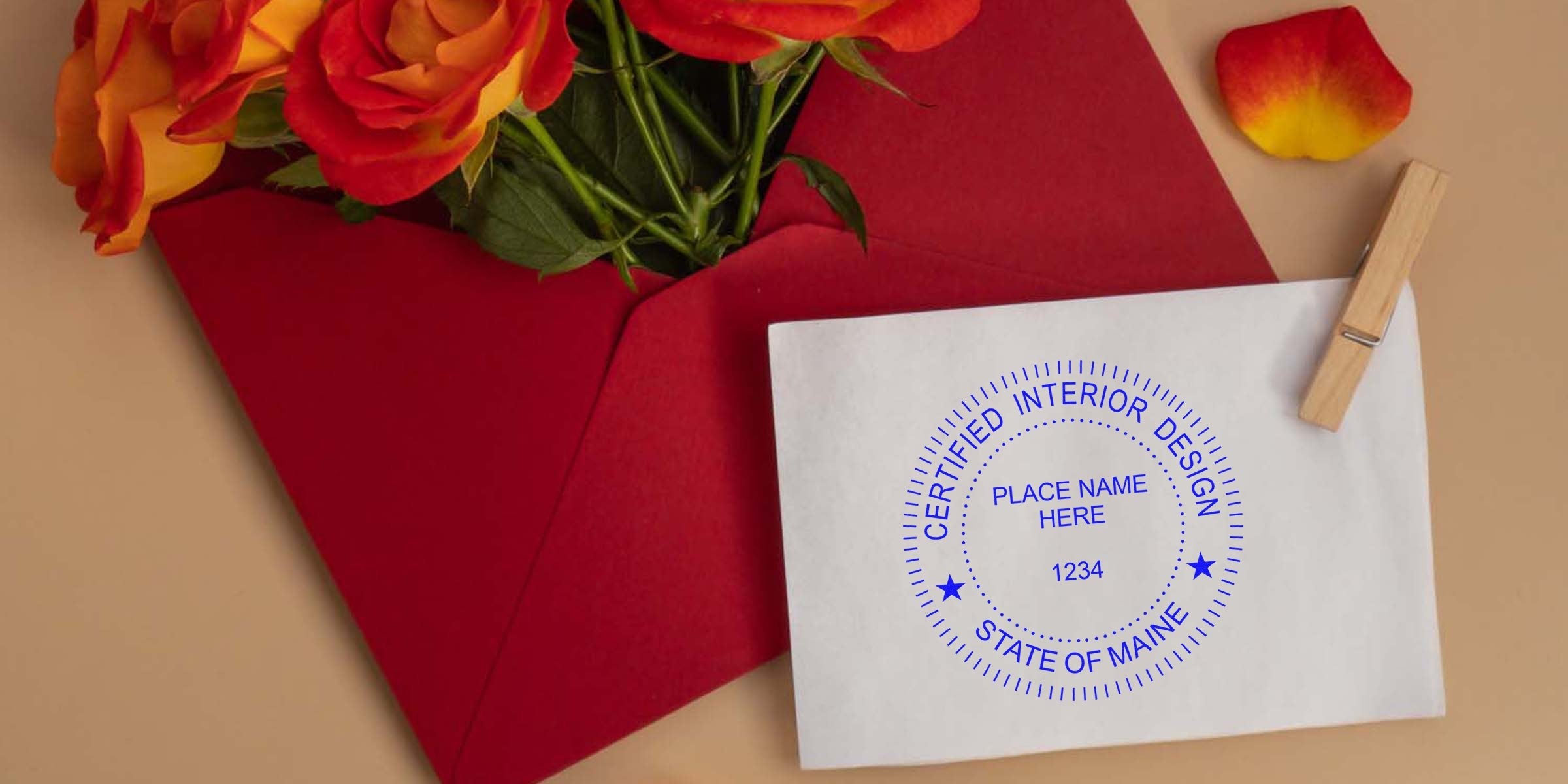 Red envelope with orange roses and a certified Maine interior designer certificate on a white card clipped by a wooden clothespin, showcasing space optimization tips.