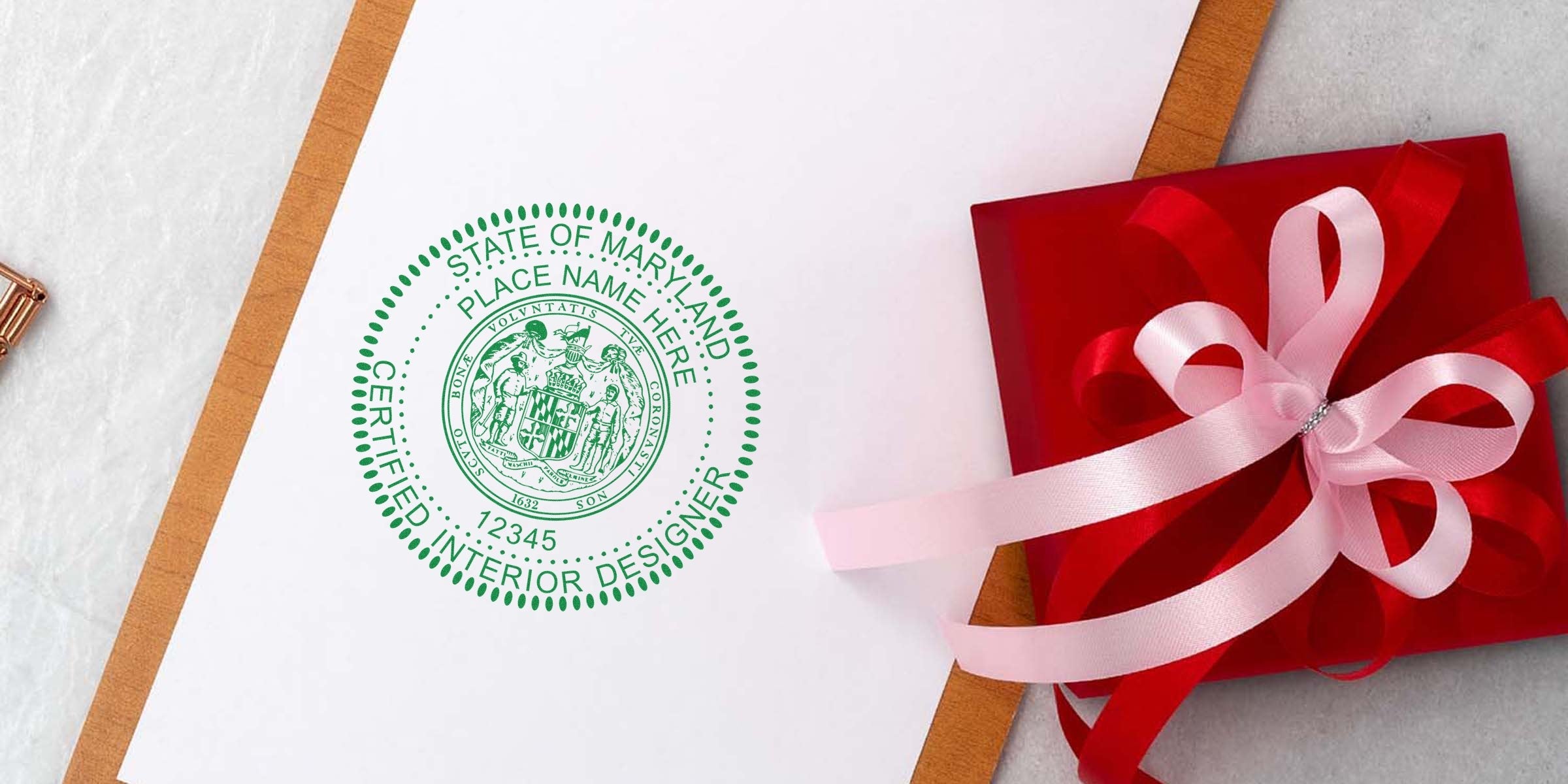 Maryland certified interior designer stamp on white paper next to red gift box with pink ribbon, showing Maryland interior design guidelines and seal requirements.
