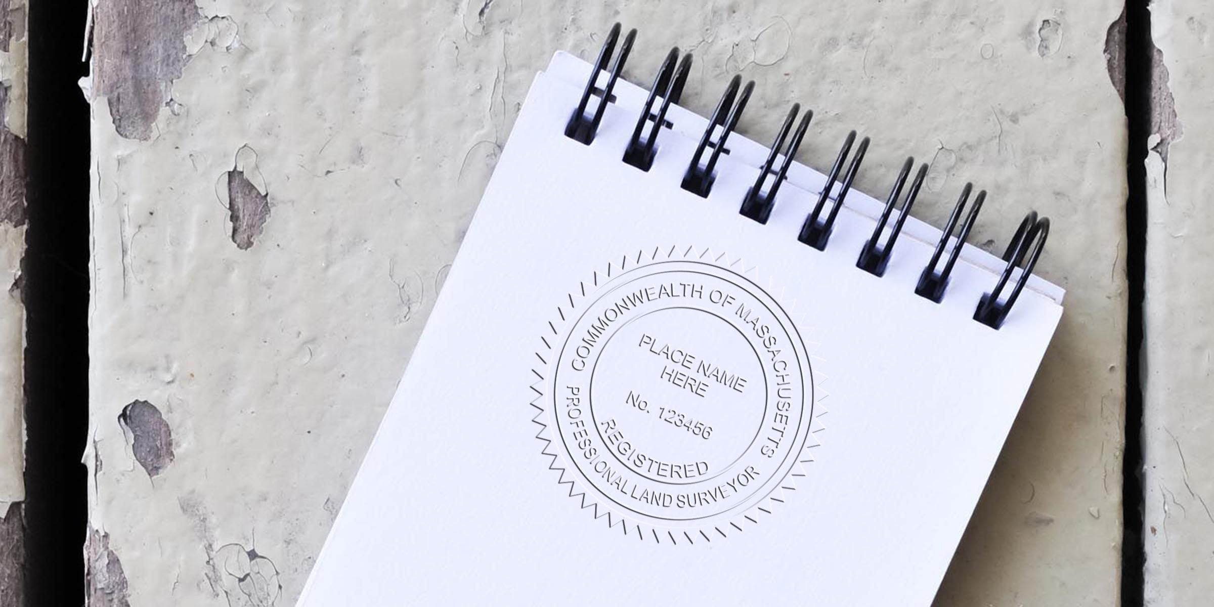 Massachusetts land surveyor stamp on white spiral notebook, emphasizing land surveyor regulations in Massachusetts for professional surveying services.